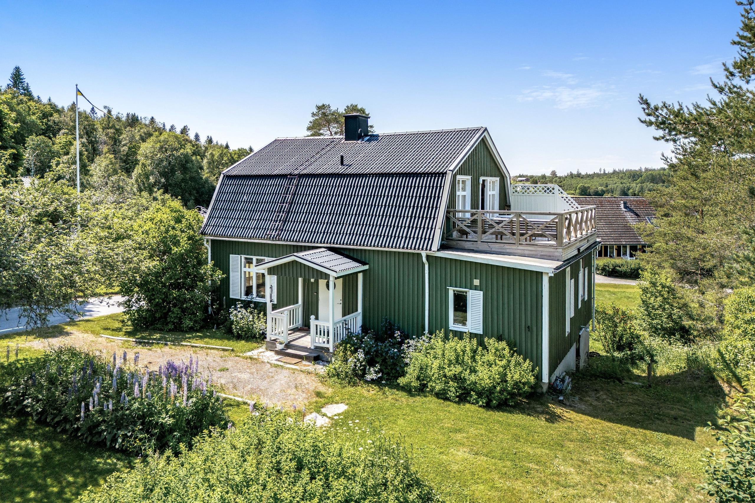 Exterior view of the green coliving house surrounded by garden and trees in summer