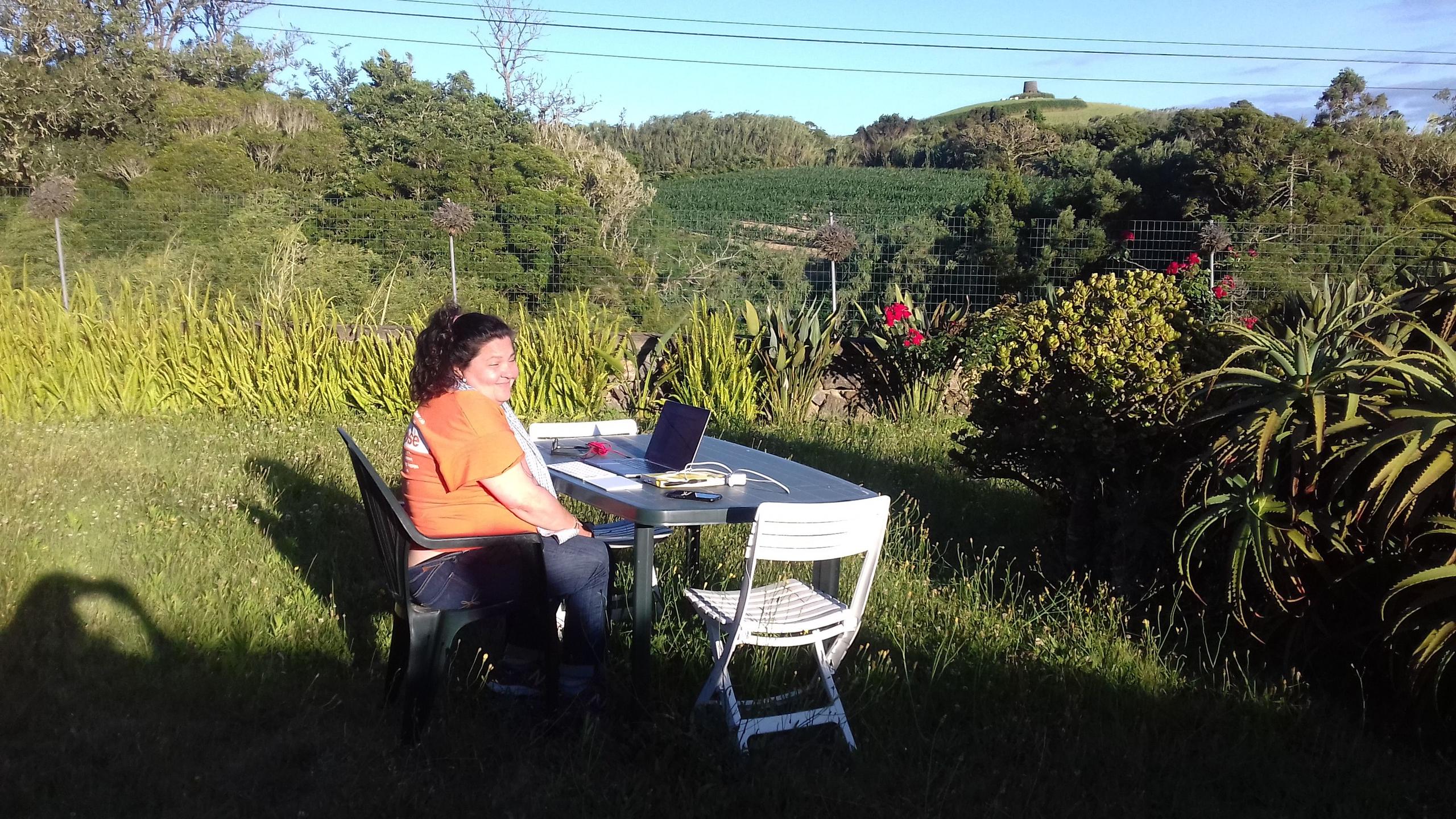 A guest working on a laptop at an outdoor table in the garden, surrounded by lush greenery