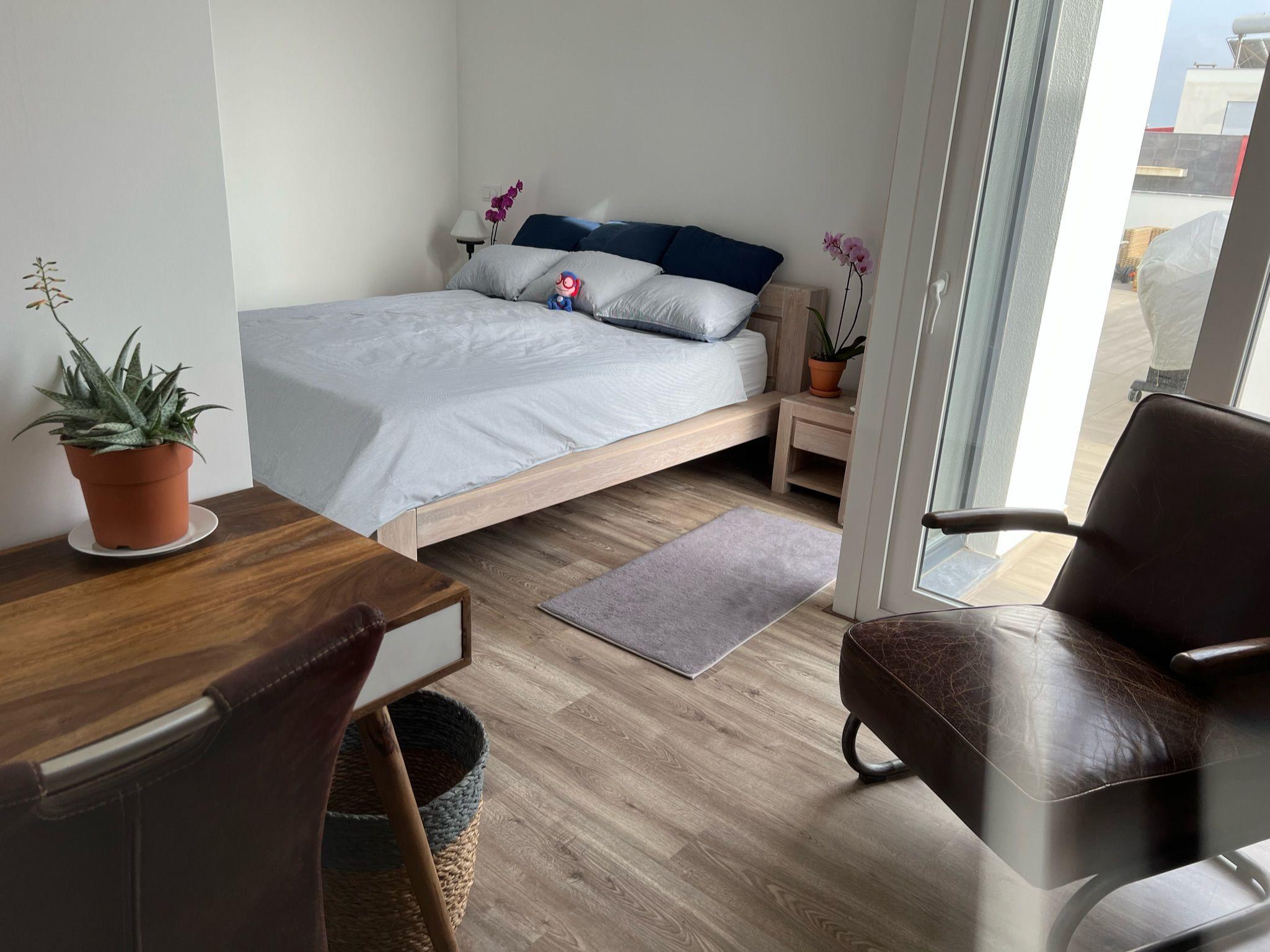 Wide-angle view of the Ensuíte Supertubos bedroom with desk, chair, and terrace access