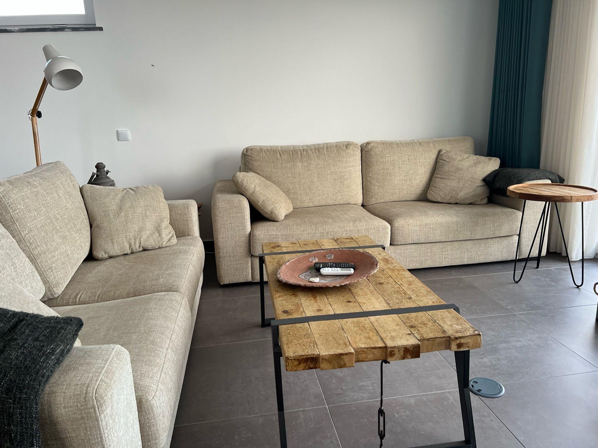 The shared living room with two beige sofas and a rustic wooden coffee table
