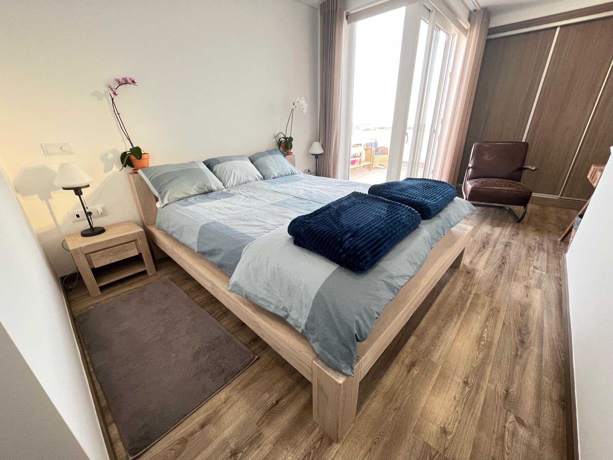 Spacious bedroom with queen-size wooden bed, wardrobe, and terrace access in the Ensuíte Supertubos