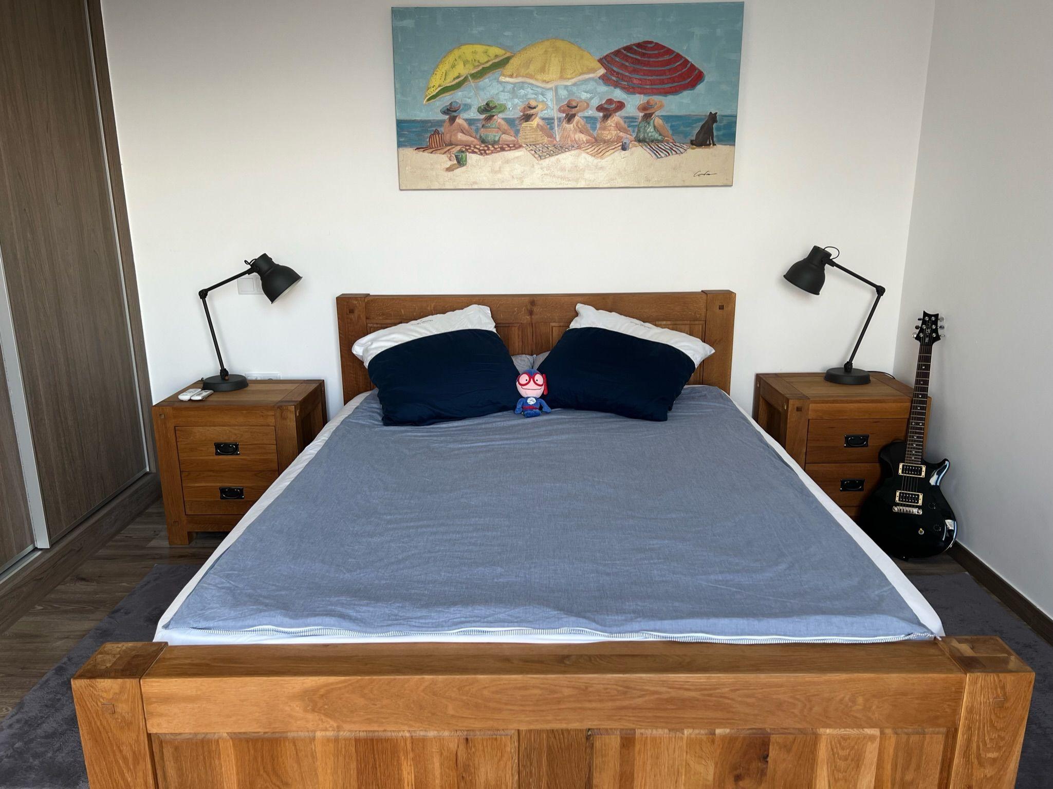 Queen-size bed with wooden headboard and bedside tables in the Ensuíte Cantinho room