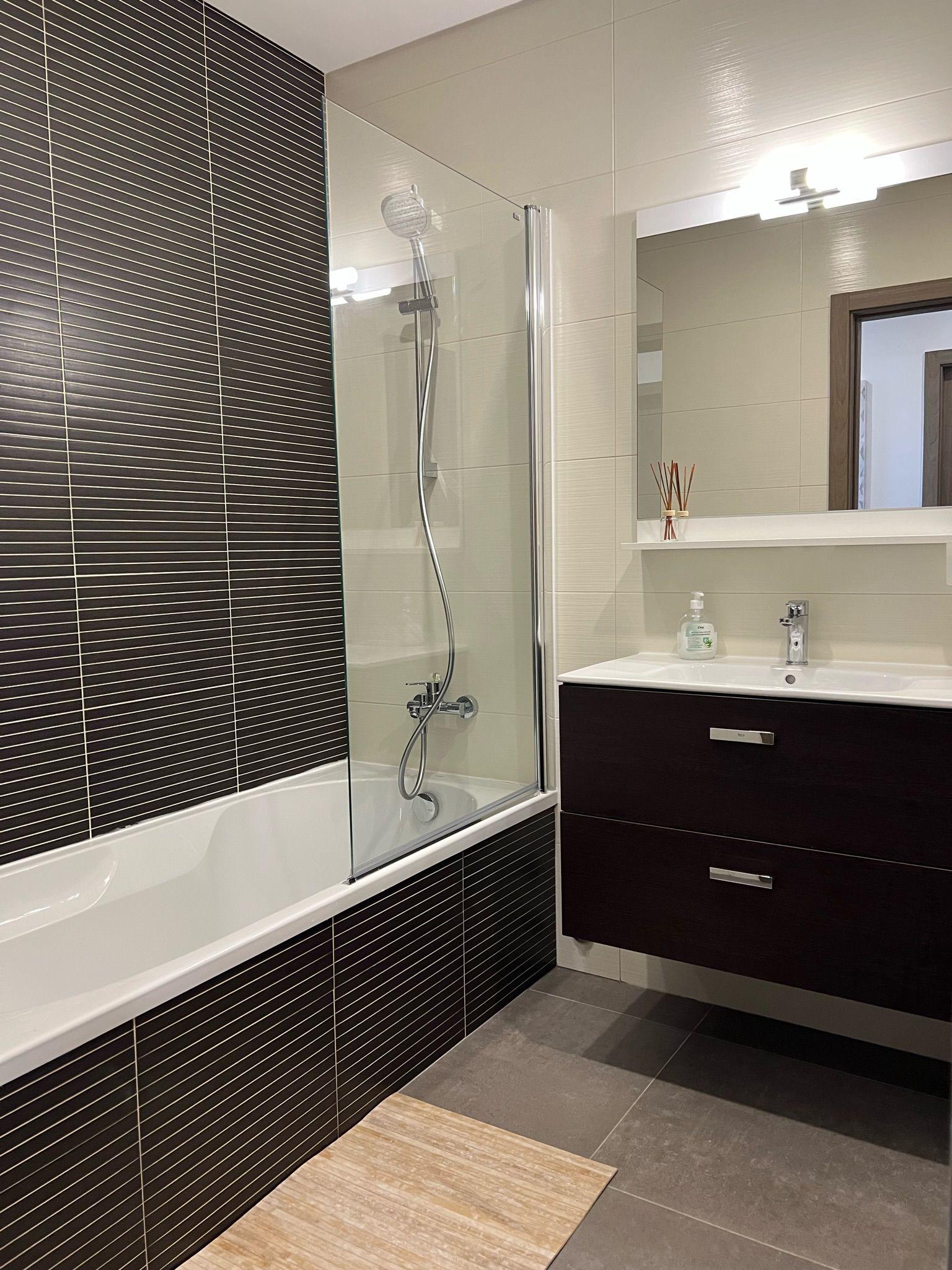 Shared bathroom with bathtub, shower, heated towel rack, and vanity unit