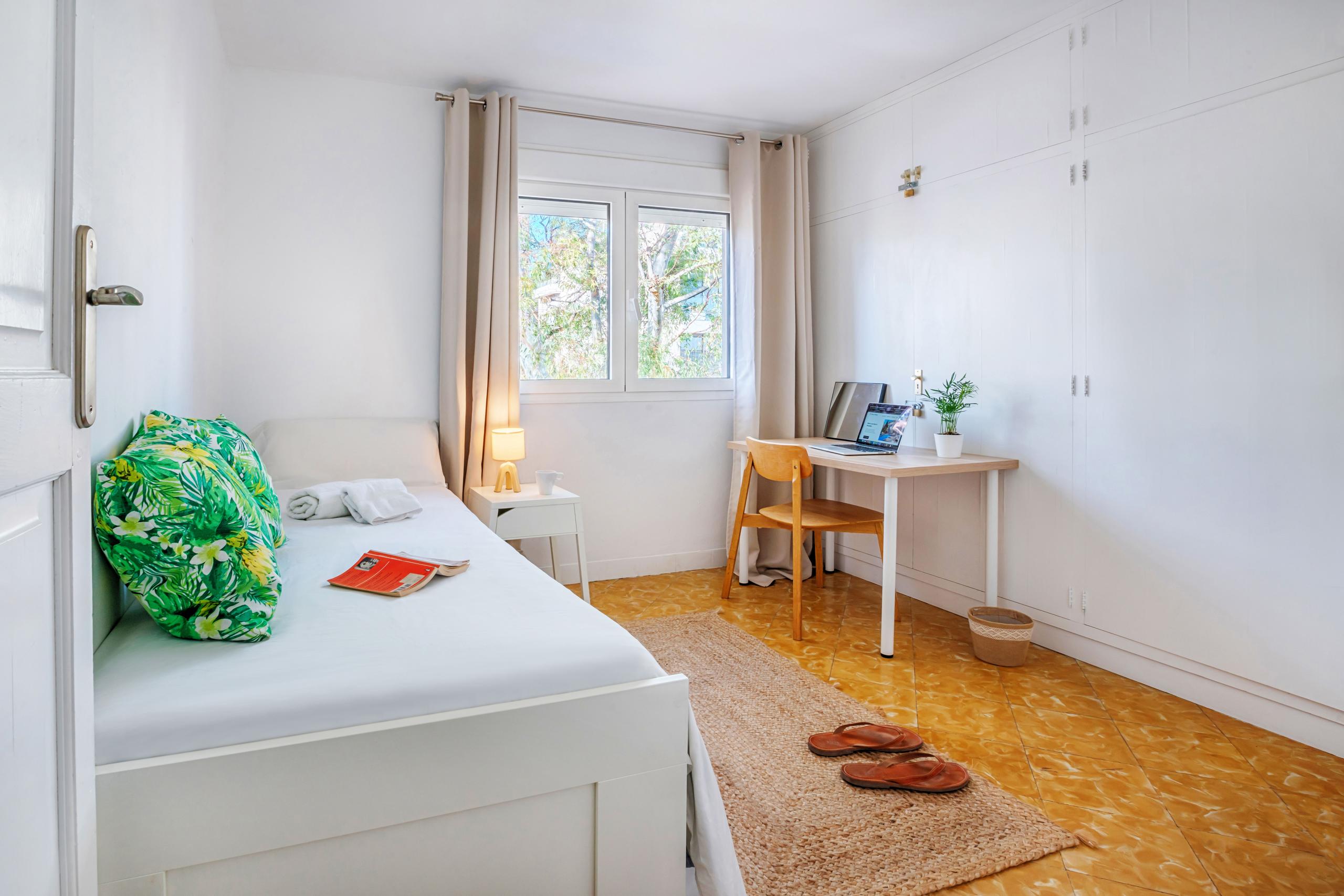 Cozy private single bedroom with a single bed, desk with laptop, wardrobe, and window with natural light