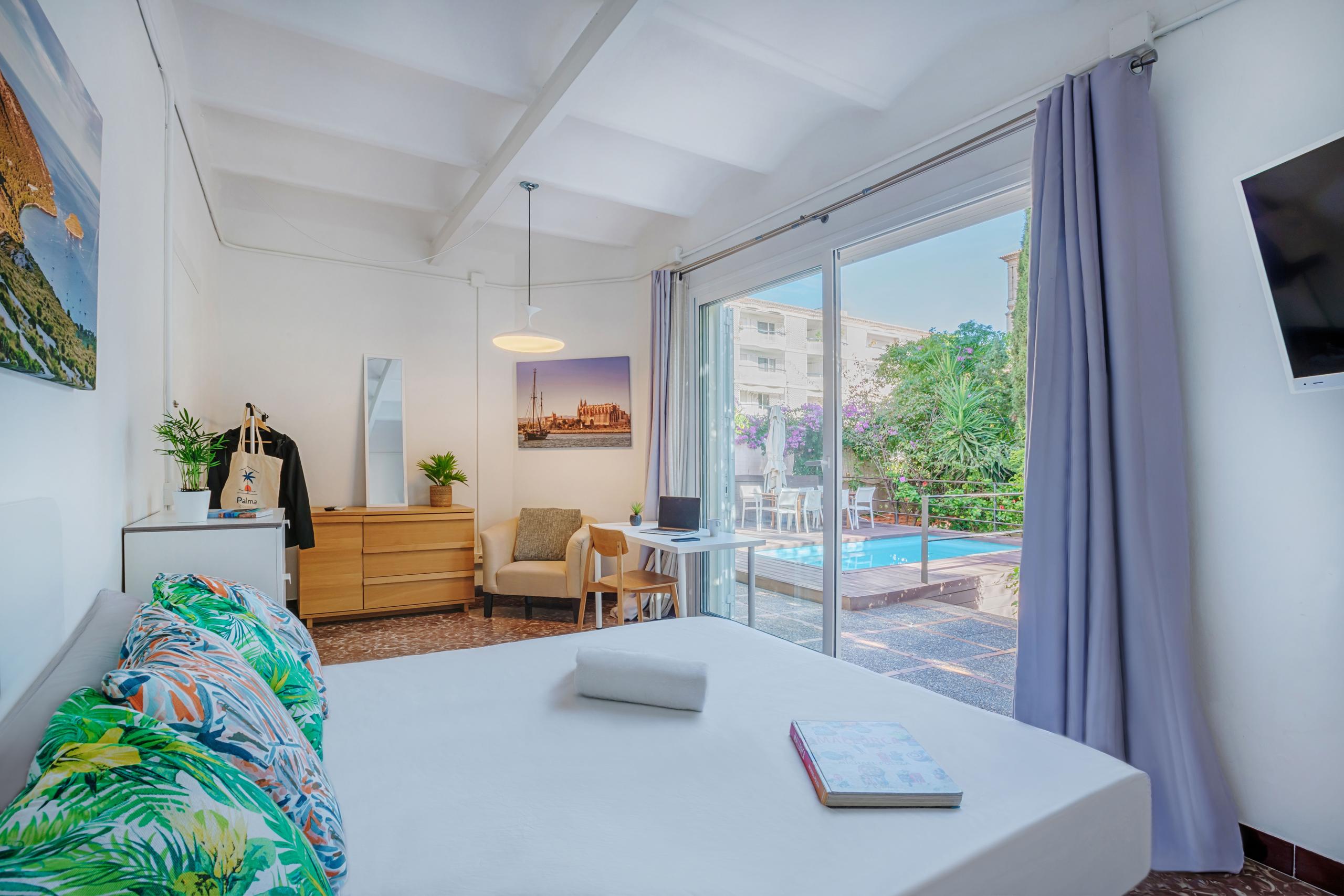 Double bedroom with direct access to the garden and pool through sliding glass doors, desk, dresser, and tropical decor