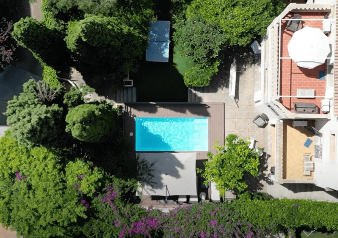 Aerial drone view of Villa Armadans garden showing the swimming pool, ping pong table, lush trees, and surrounding terrace areas