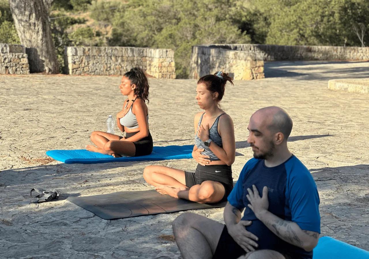 Three residents doing meditation/yoga outdoors on yoga mats in a natural setting