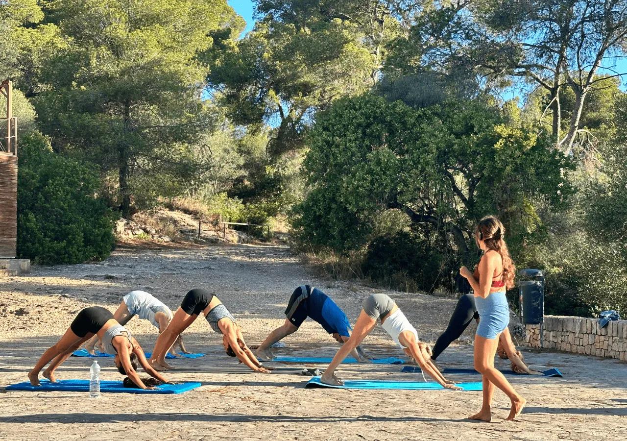 Group yoga class outdoors with an instructor leading residents through poses in a natural setting