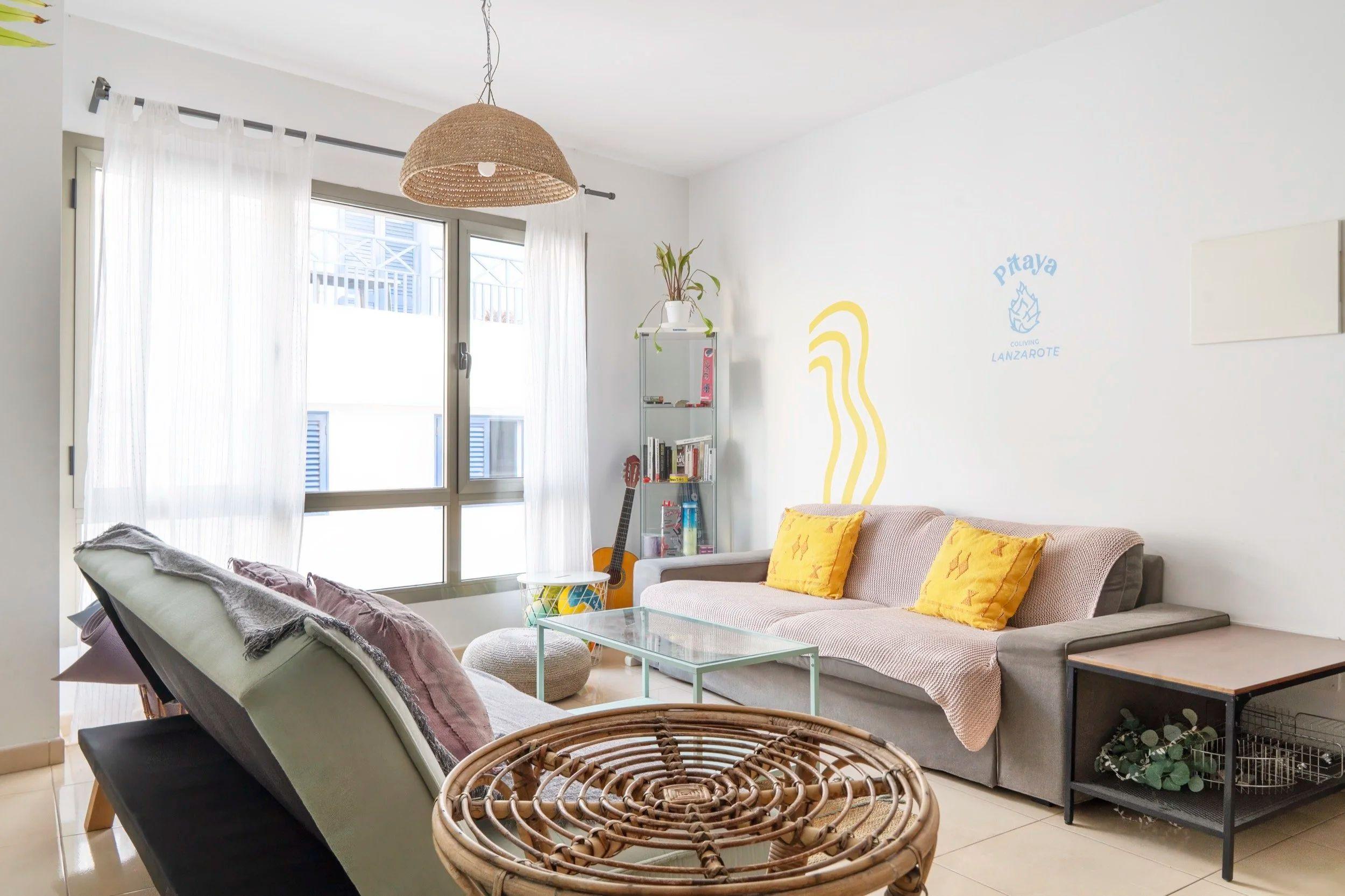 Living room at Pitaya Coliving with cozy sofas, board games, yoga mats, and a projector screen