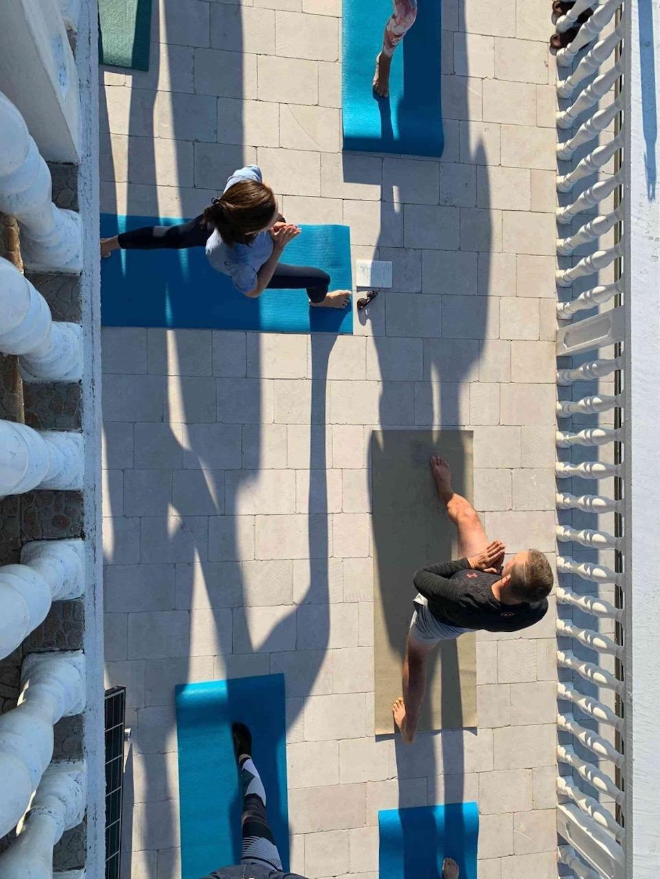 Residents doing yoga on blue mats on the rooftop terrace, aerial view