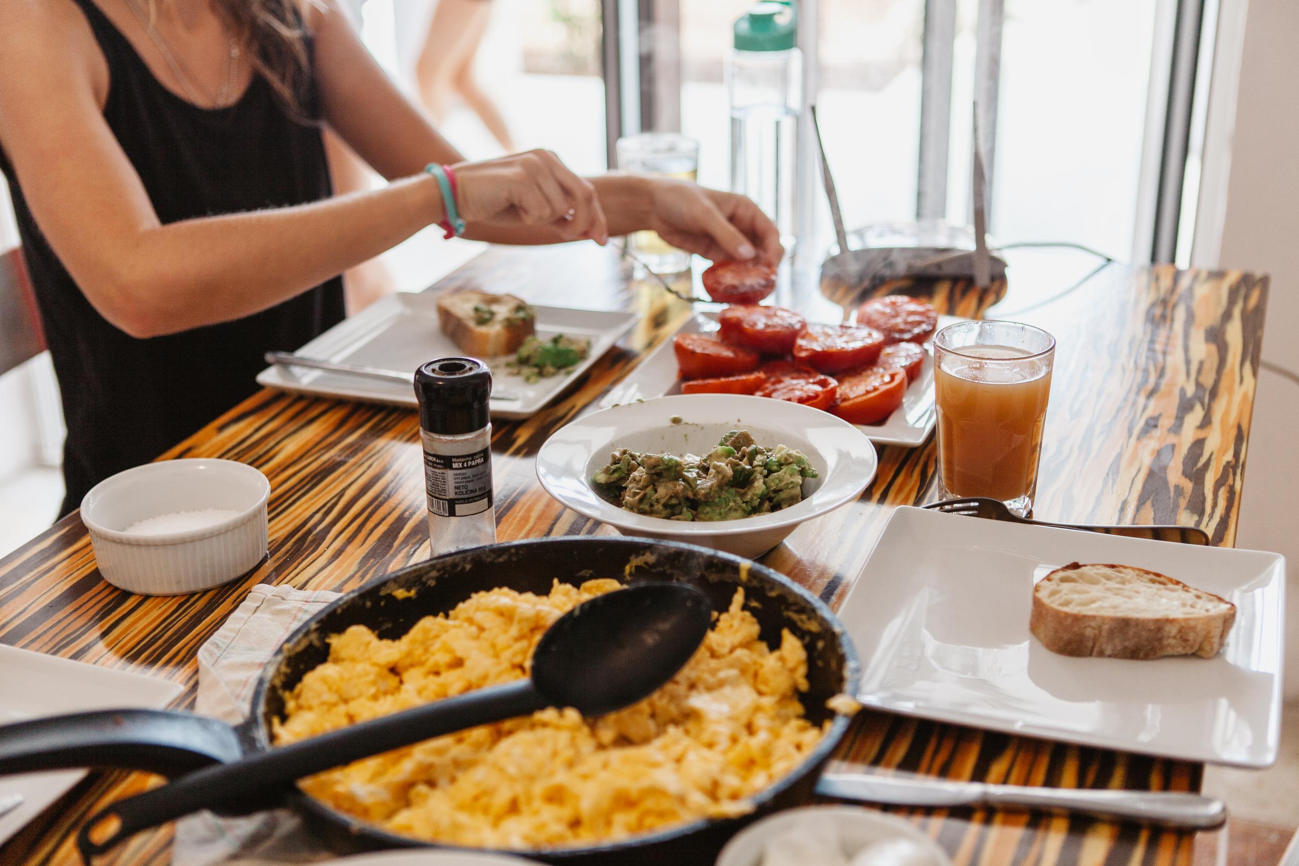 A resident eating at the dining table with food spread including scrambled eggs, tomatoes and avocado