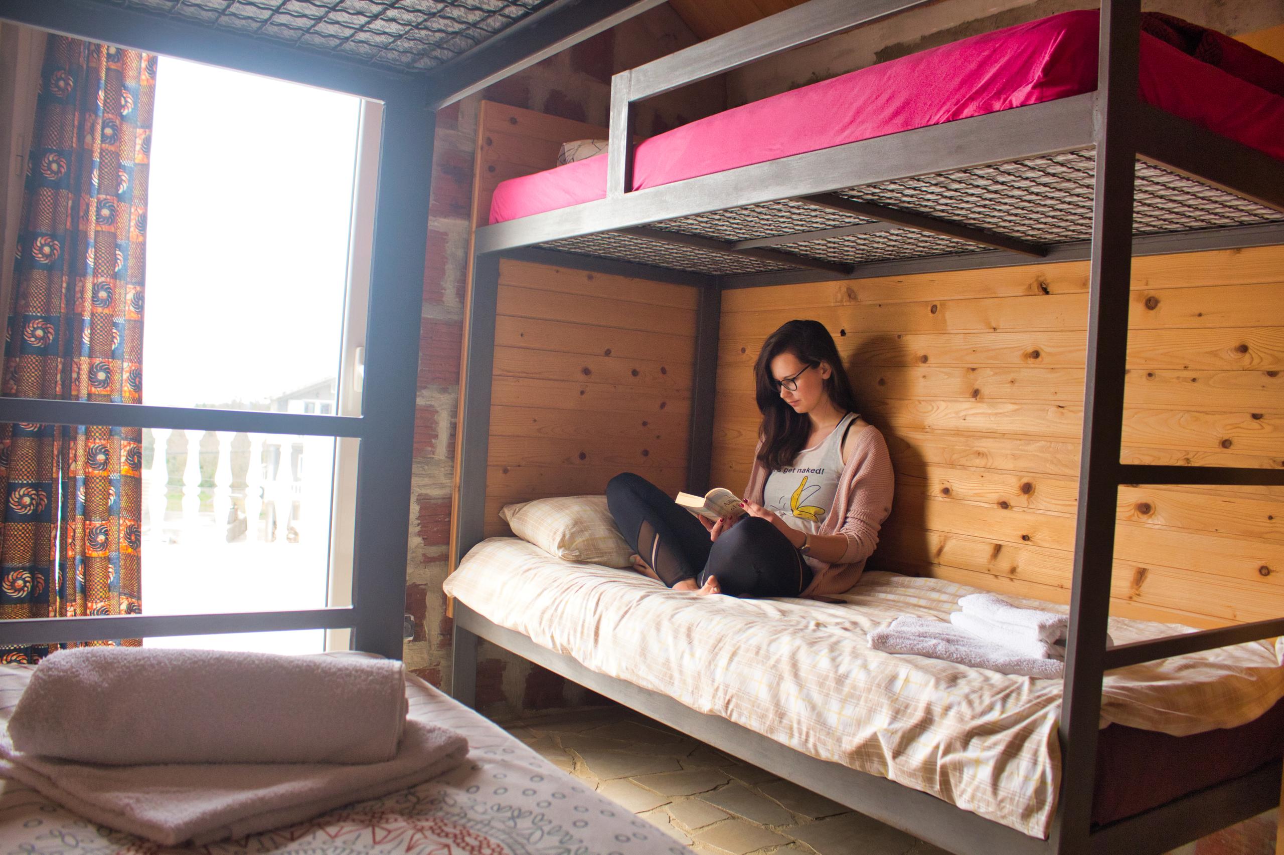 Standard private room with bunk beds and a window, resident reading on the lower bunk