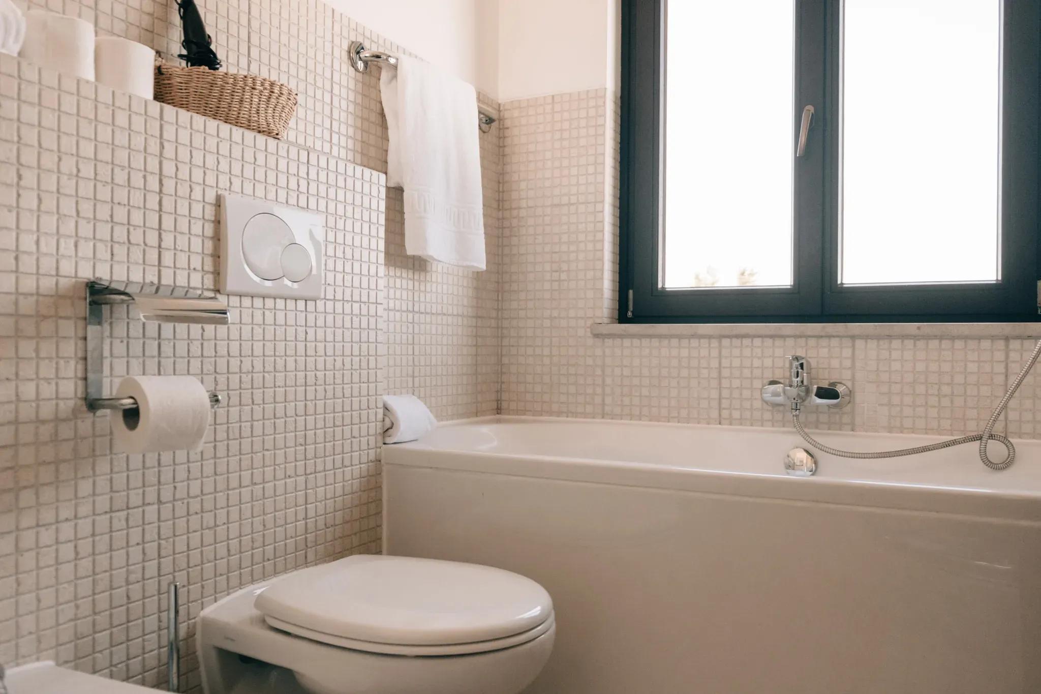 Bright and modern bathroom with a bathtub, tiled walls, and window at POMAR na praia
