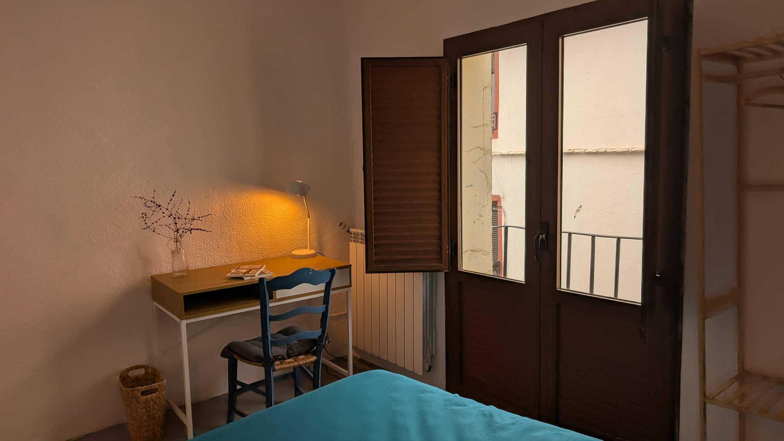 The Goldin room showing a desk, books, lamp, chair, dried grass vase, balcony window and connectivity cube