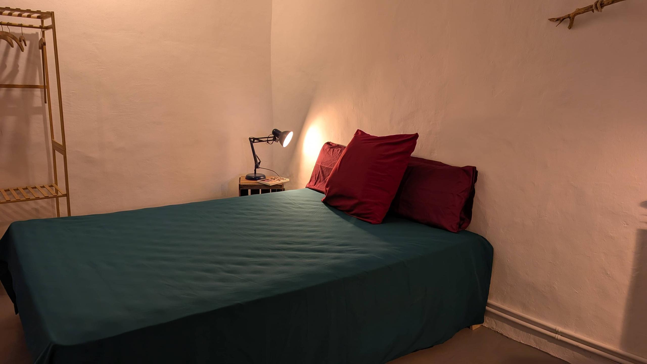 The Woodman room showing a bed and nightstand with a lamp