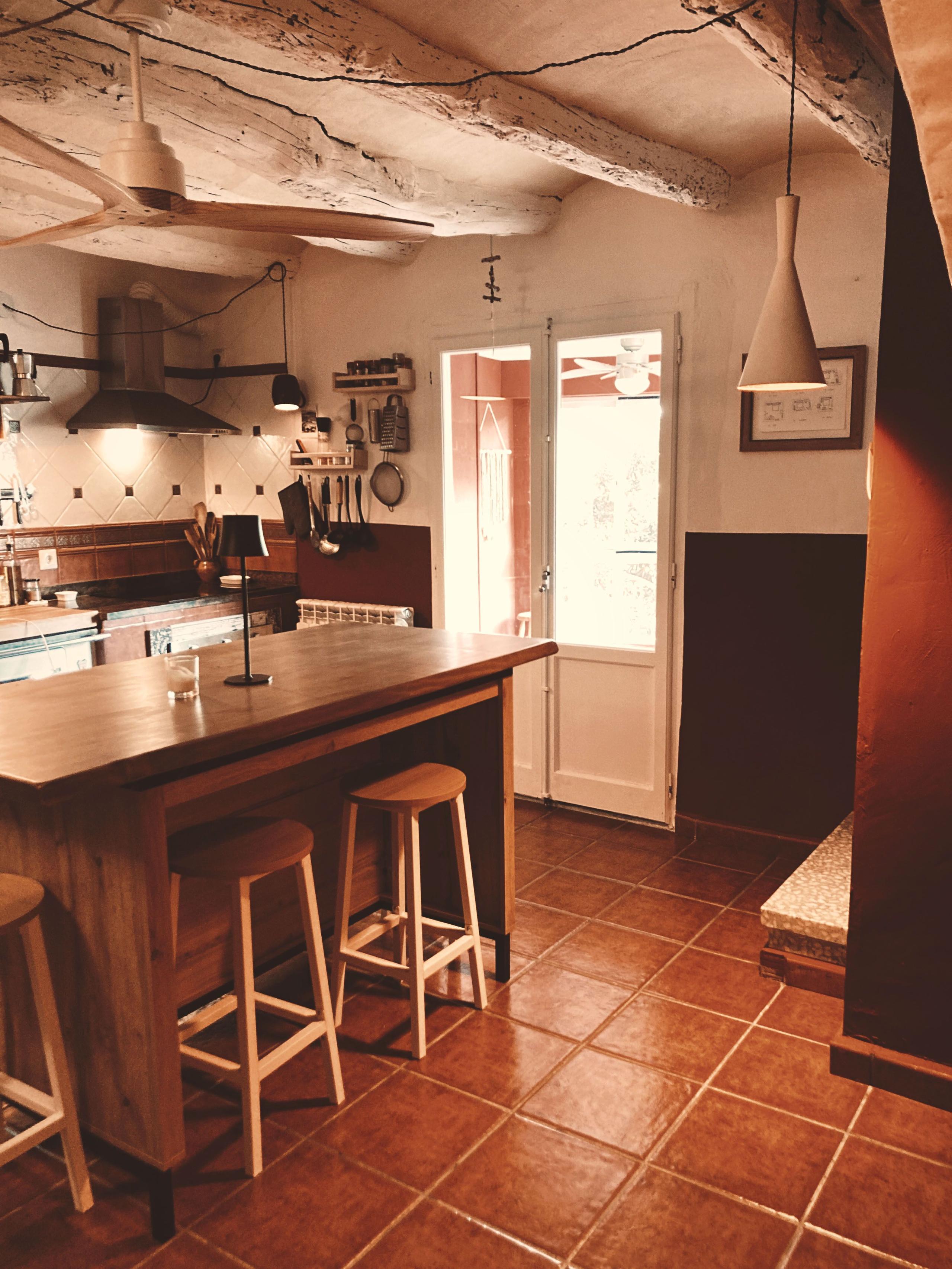 Kitchen showing the central island with white stools and the exit door to the glass gallery leading to the garden