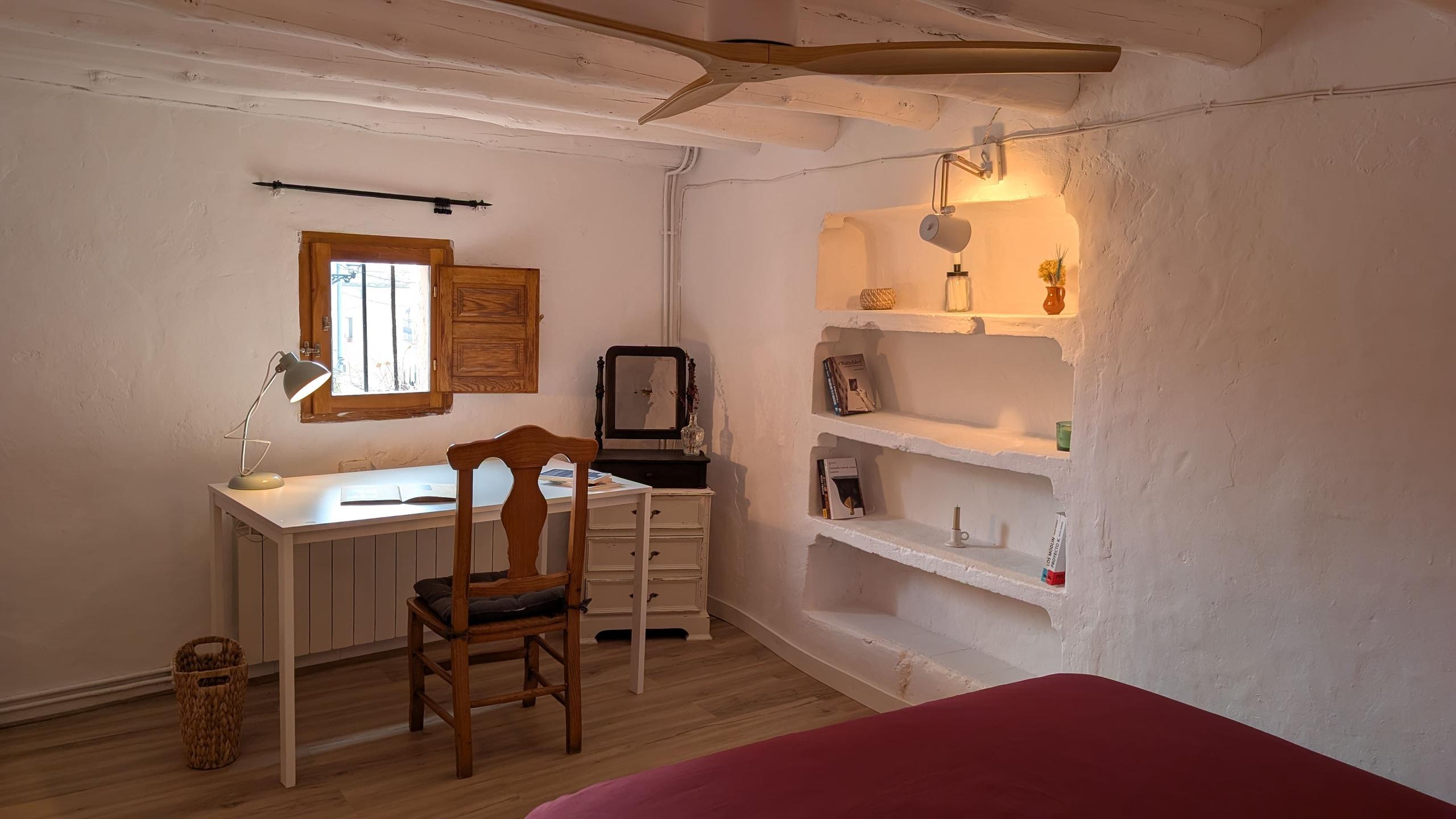 The Arbus room showing a desk, books, lamp, chair, connectivity cube with electrical outlets and USB ports, a built-in bookshelf and street window