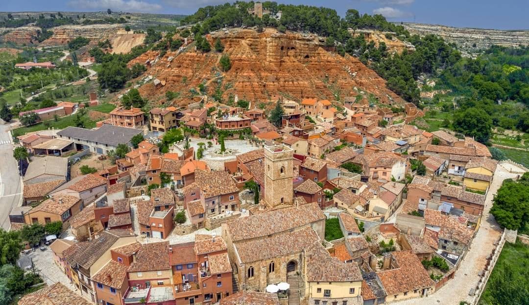 Panoramic view of Anento village with red rooftops and a tower, mountainous surroundings