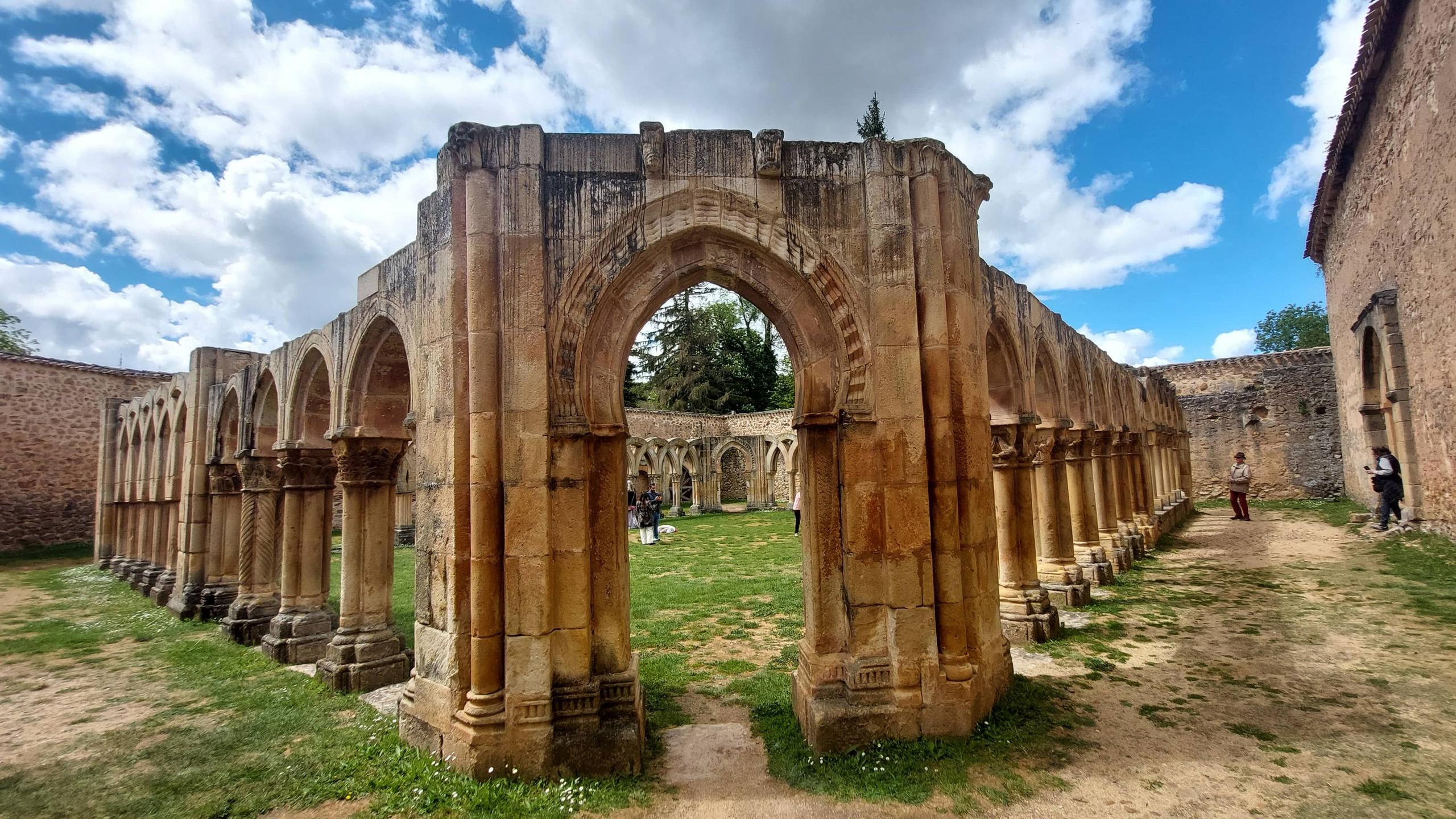 Ancient ruins with arches, green grass and blue sky — San Juan de Duero cloister in Soria