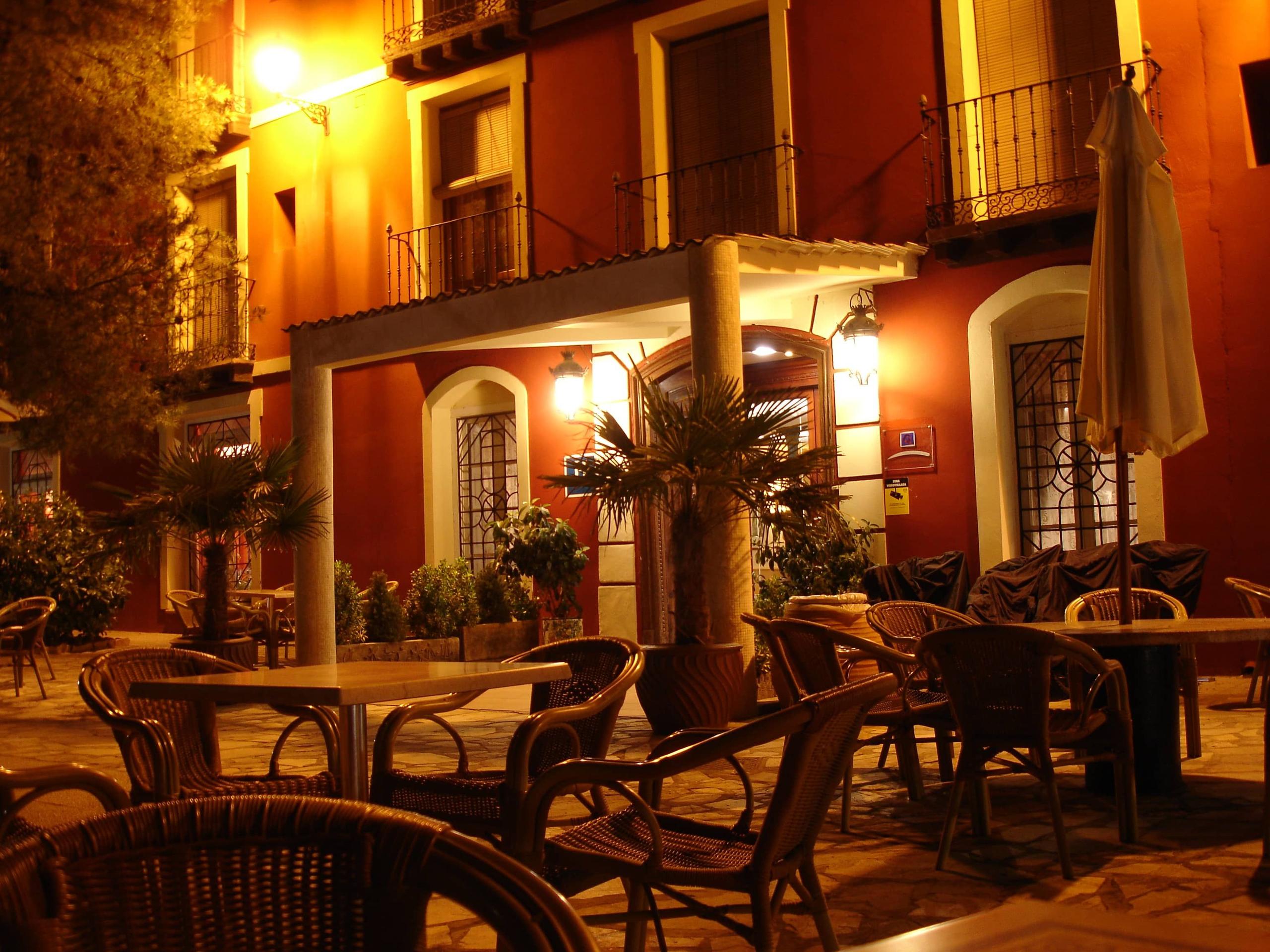Restaurant with outdoor tables and chairs, red facade at night — Balneario Paracuellos de Jiloca