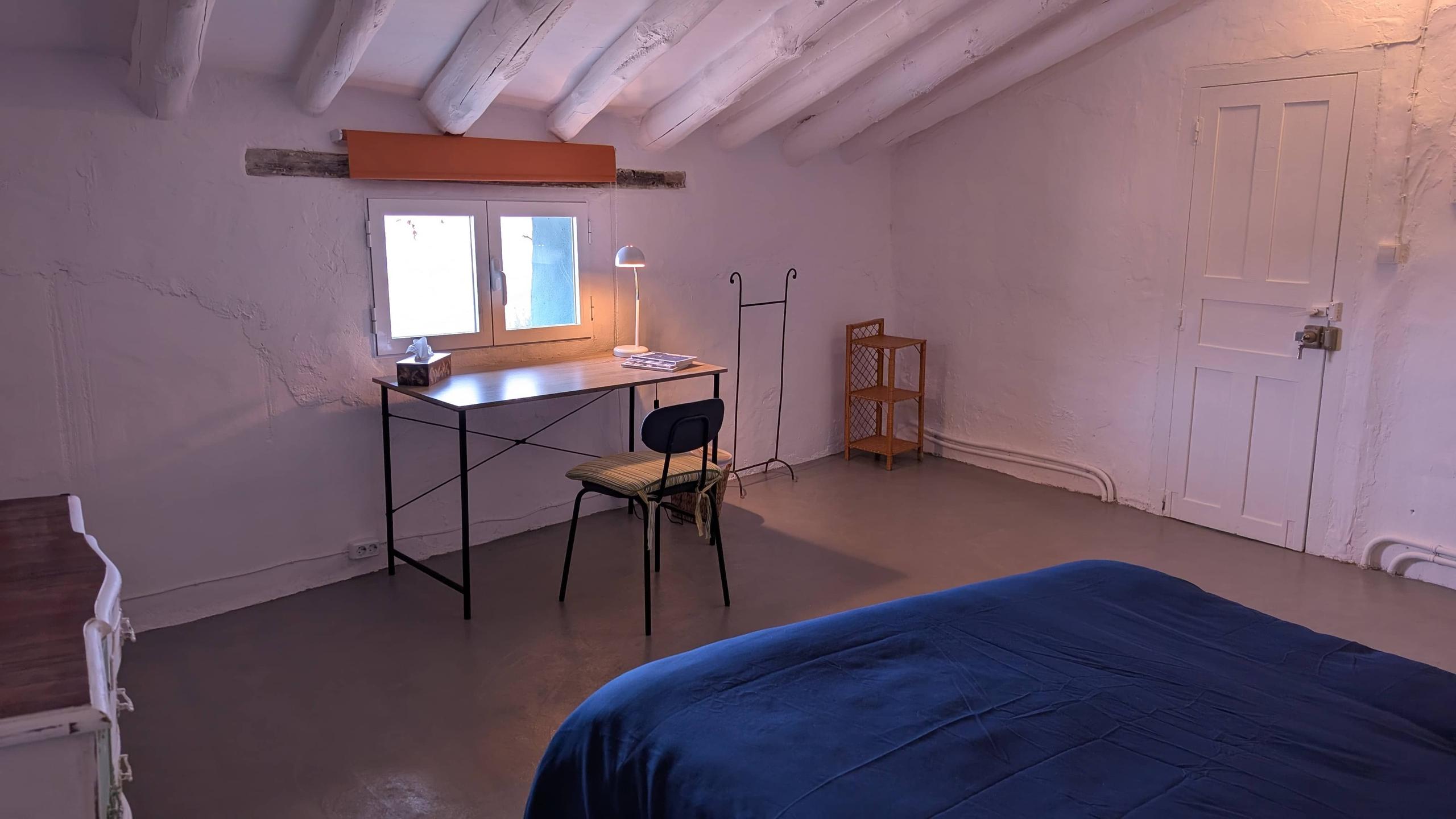 The Sally room showing a street window, study desk, lamp, chair, open books, part of a bed, dried flowers, auxiliary furniture and connectivity cube