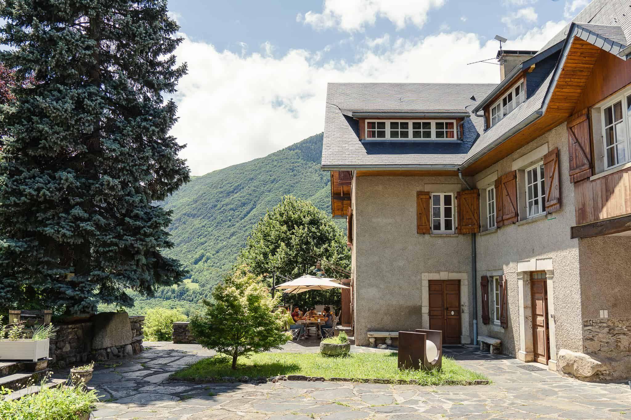 Exterior view of the Pyren'Escape chalet with Pyrenees mountains in the background, garden and outdoor seating visible