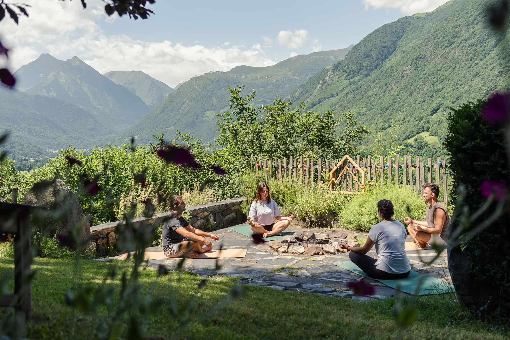 Group of guests doing yoga/meditation outdoors in the garden with Pyrenees mountain views