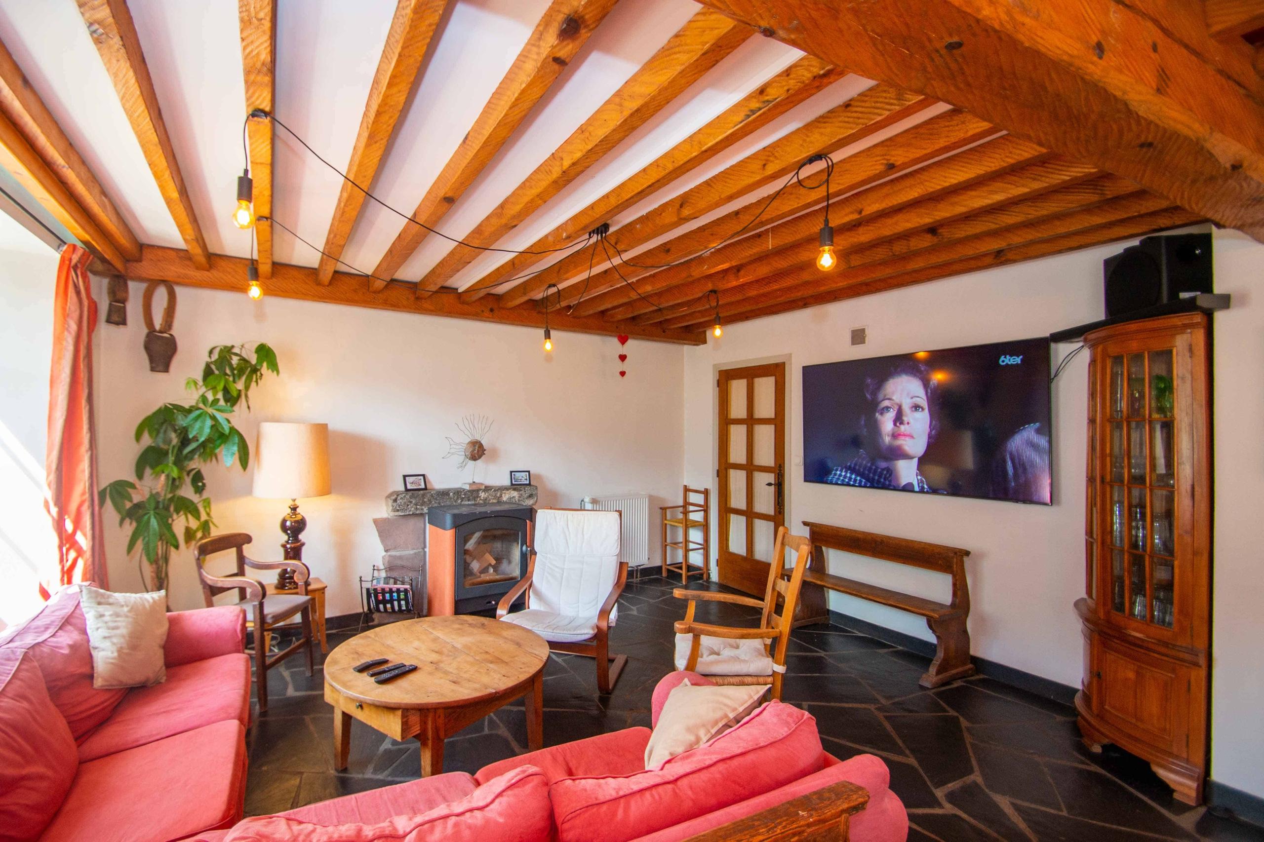 Friendly lounge area with sofa, giant TV and wood-burning stove