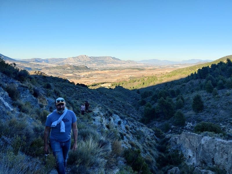 Person hiking on a mountain trail in the Sierra María-Los Vélez mountains with a wide valley view in the background