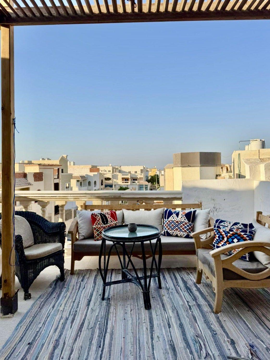 Rooftop terrace with lounge seating, colorful cushions, and city views