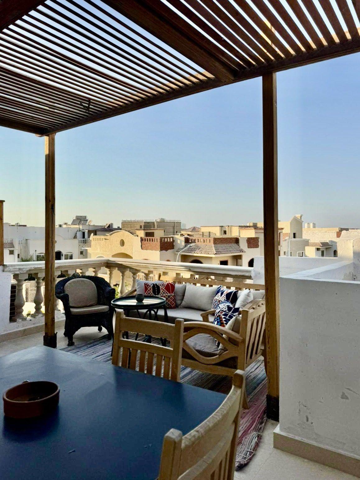 Rooftop terrace with pergola, lounge seating, and panoramic city views at sunset