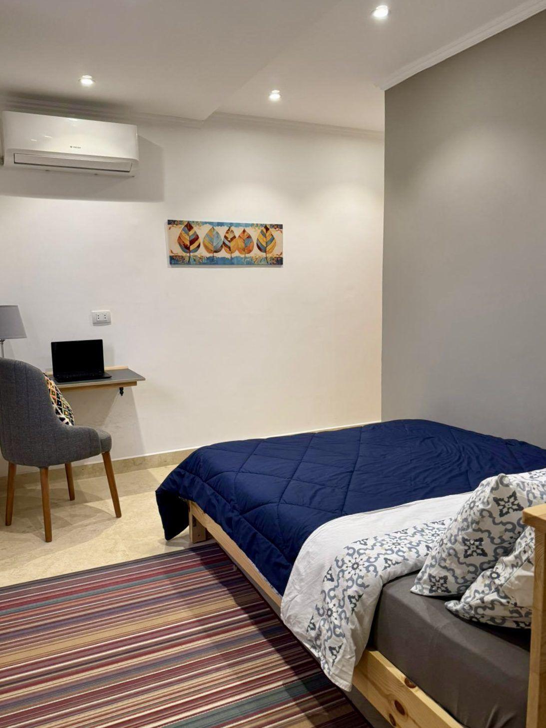 Double room with bed, work desk with laptop, and air conditioning