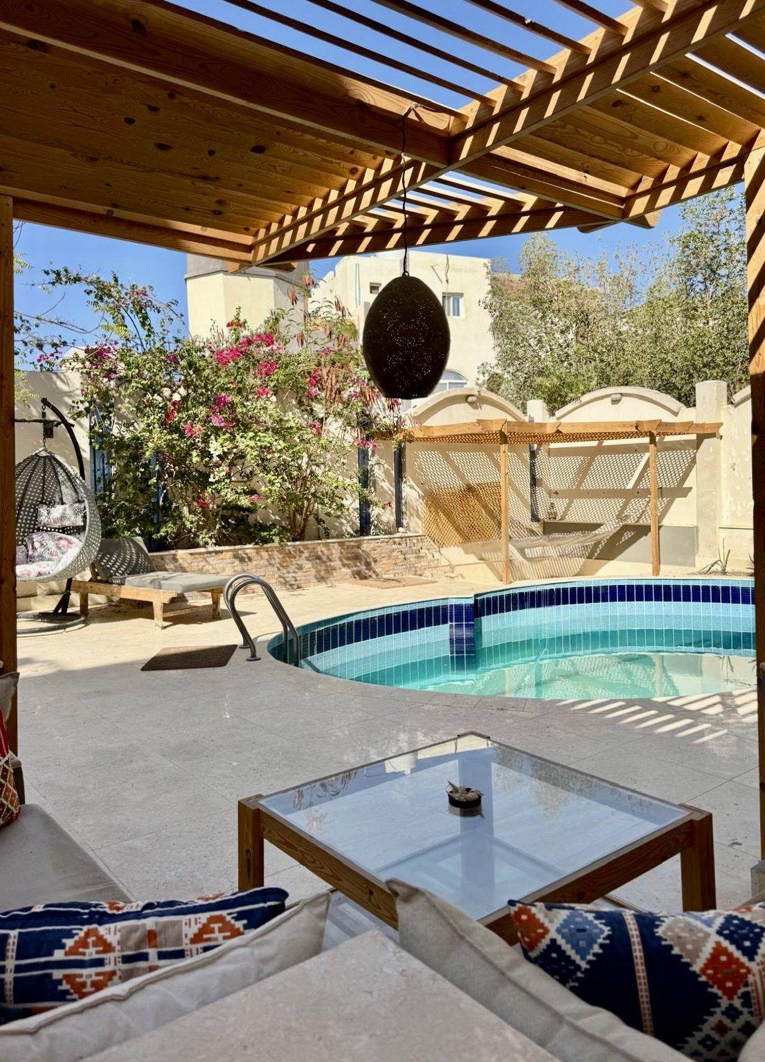 Outdoor pool area with pergola, lounge seating, and garden with bougainvillea