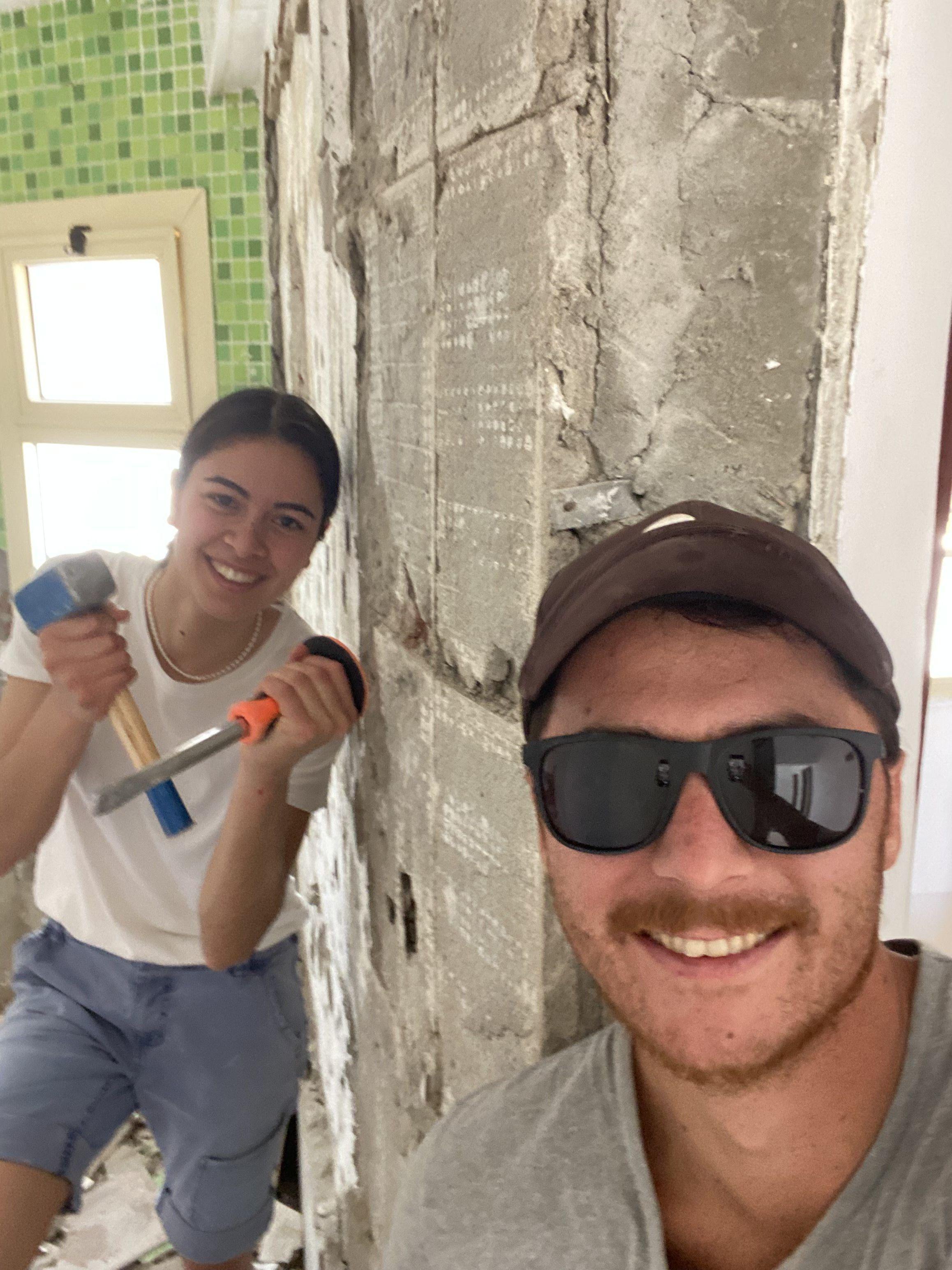 Two volunteers smiling during renovation work inside the villa