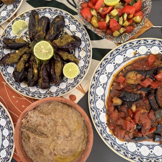 Overhead view of traditional Egyptian dishes including stuffed aubergines, salad, and dips served on decorative plates