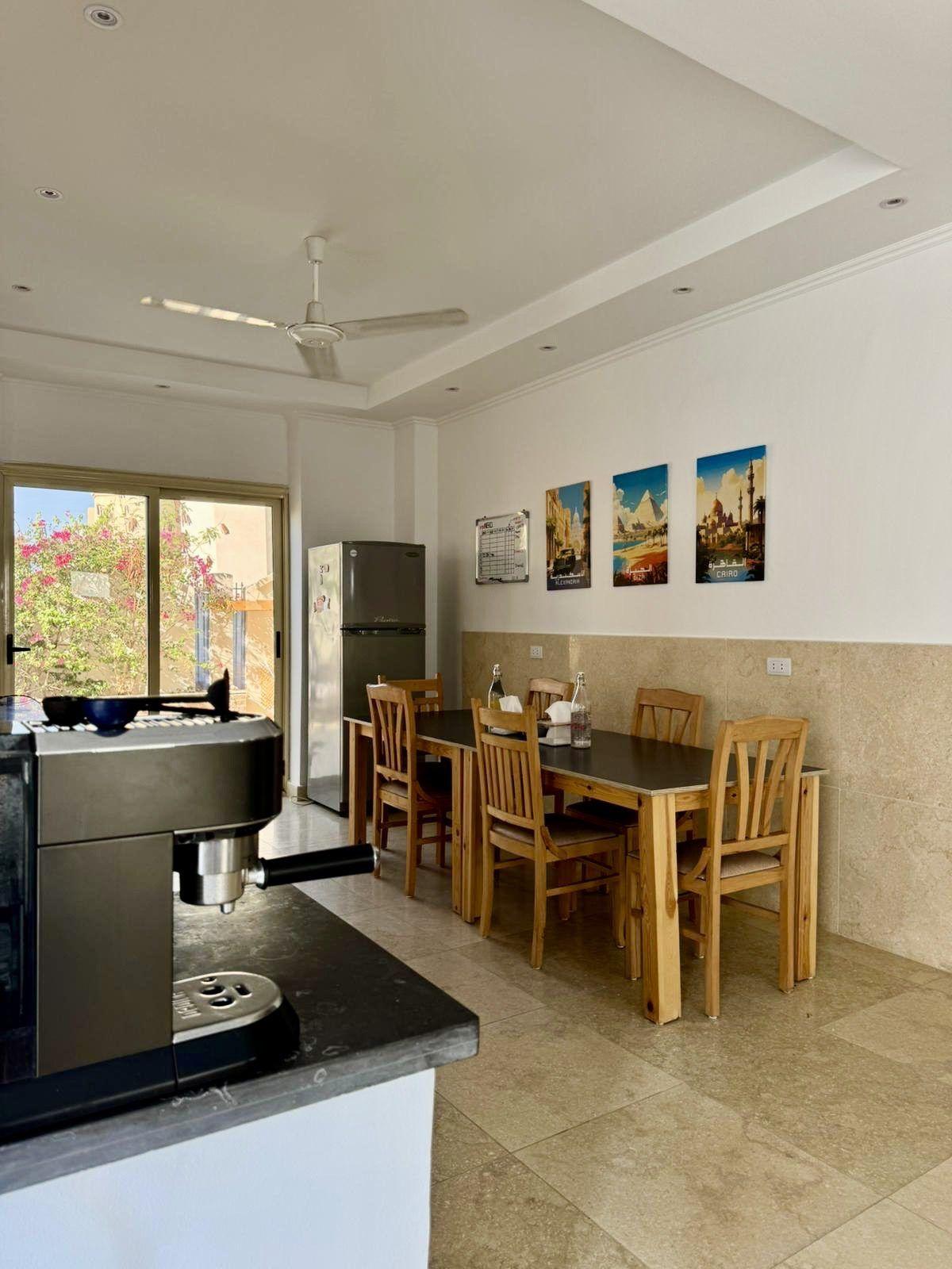 Kitchen dining area with espresso machine, dining table and chairs, and Egyptian-themed wall art