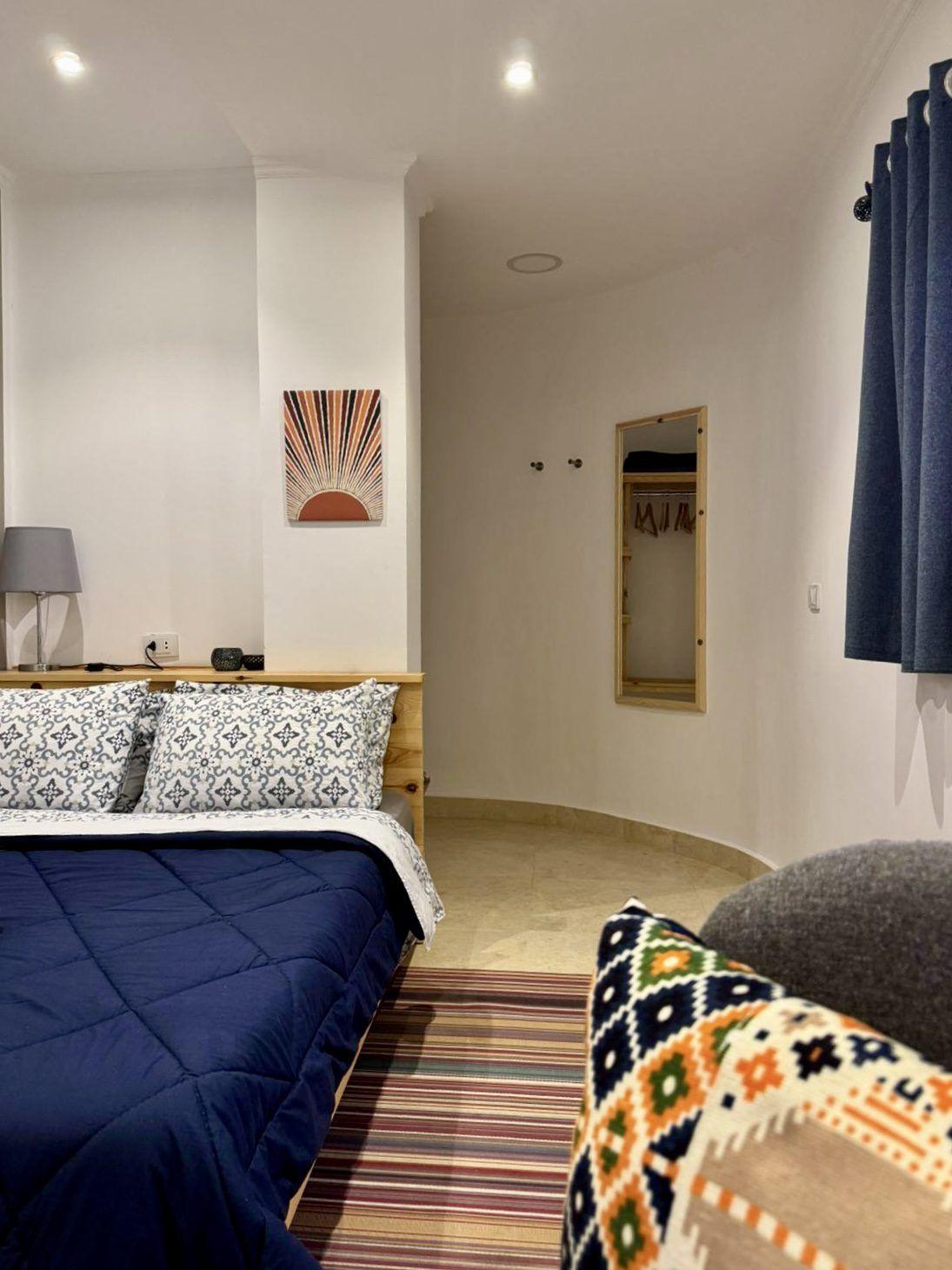 Double room with blue bedding, wardrobe, lamp, and air conditioning