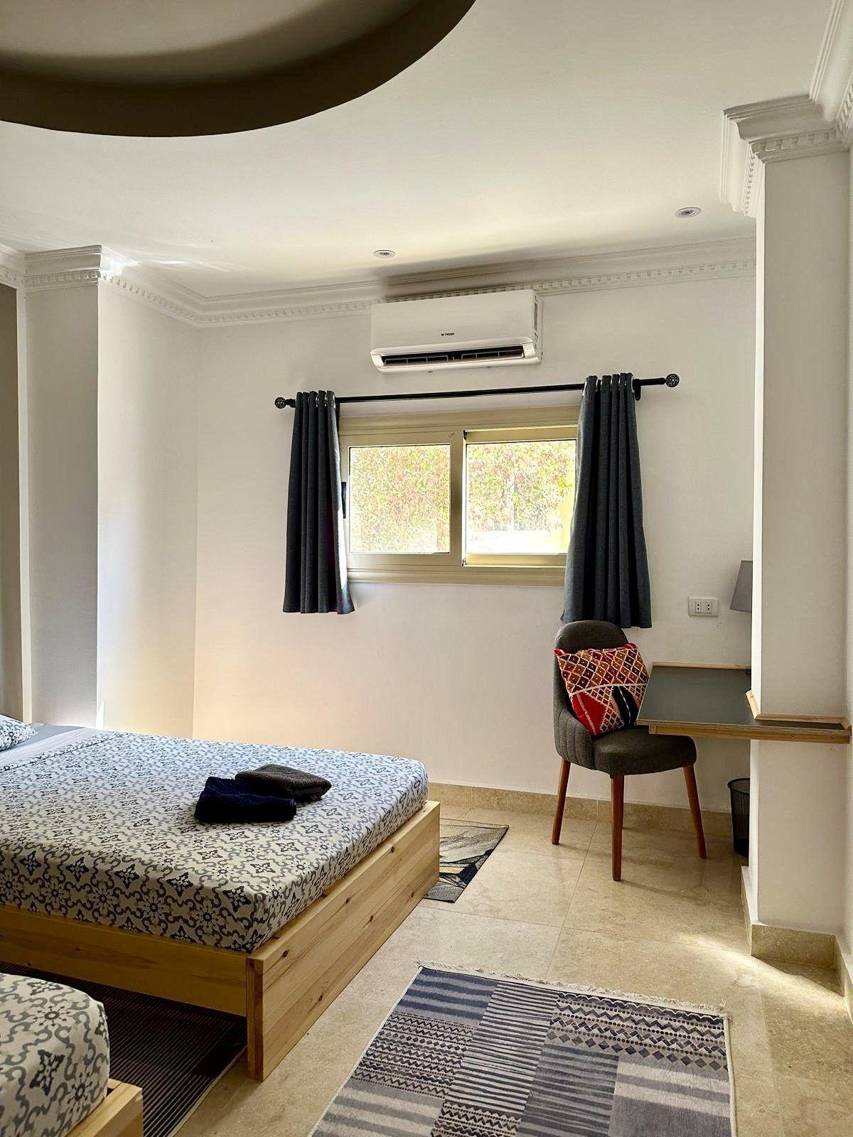 Double room with wooden bed, work desk, chair, and air conditioning