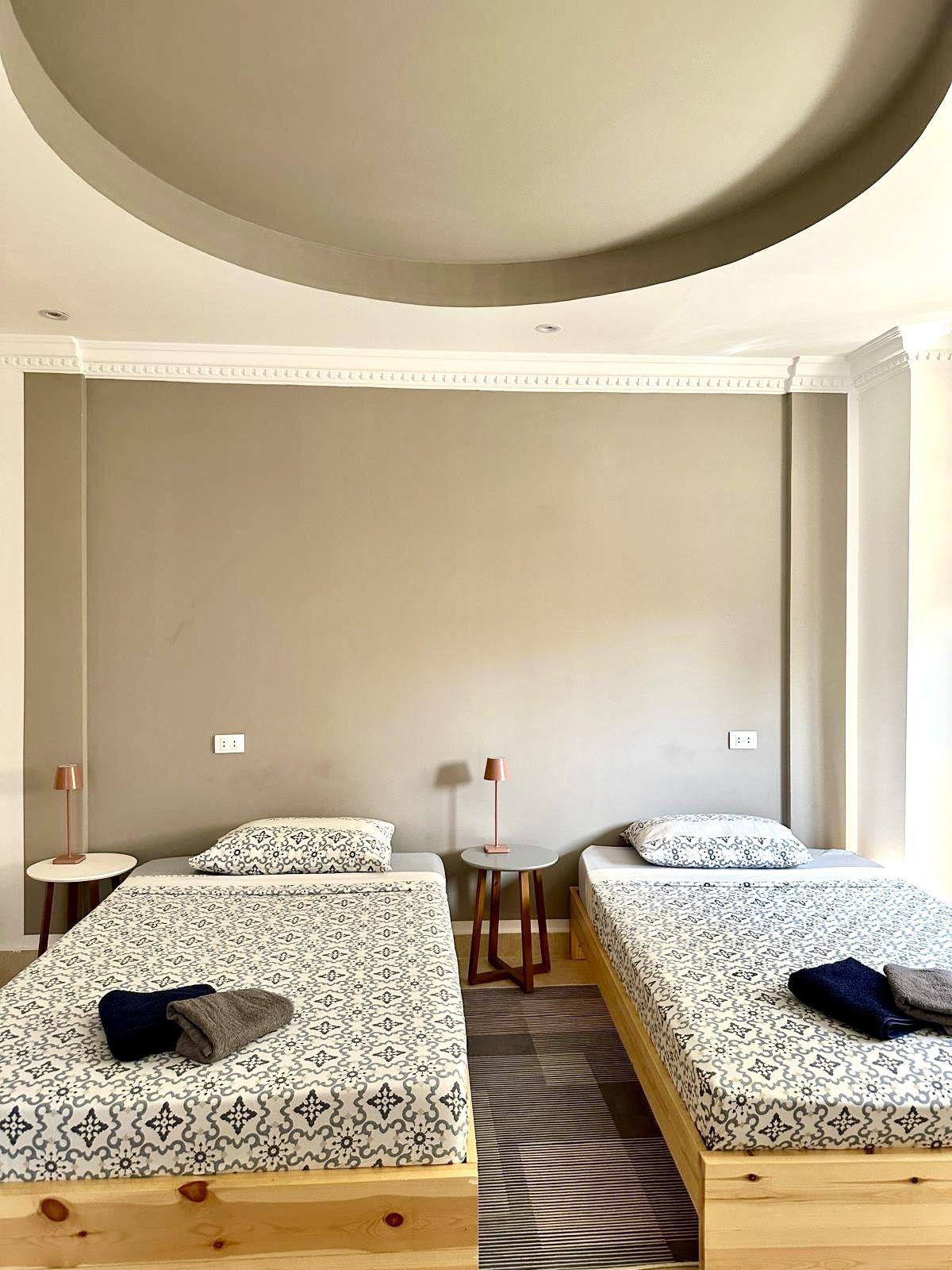 Twin room with two single beds, bedside lamps, and circular ceiling detail