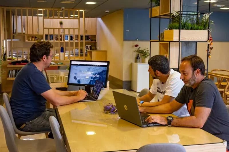 Men working on laptops at a communal table in the coworking area
