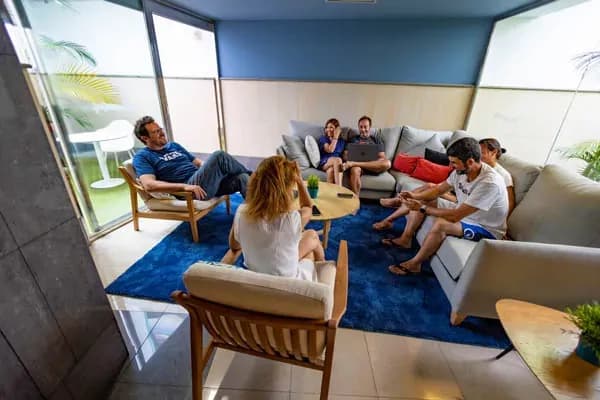 Living room with sofas, blue rug, and guests sitting together
