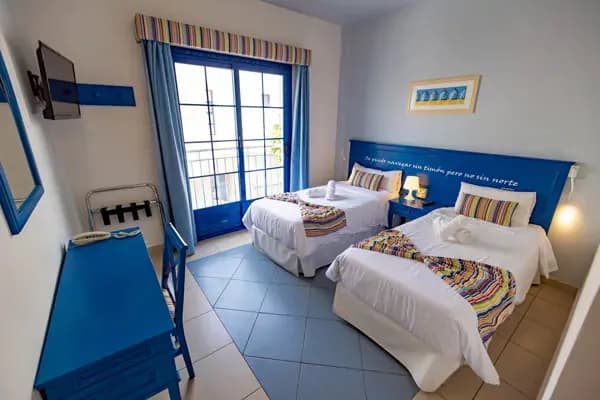 Blue-themed bedroom with two twin beds and balcony