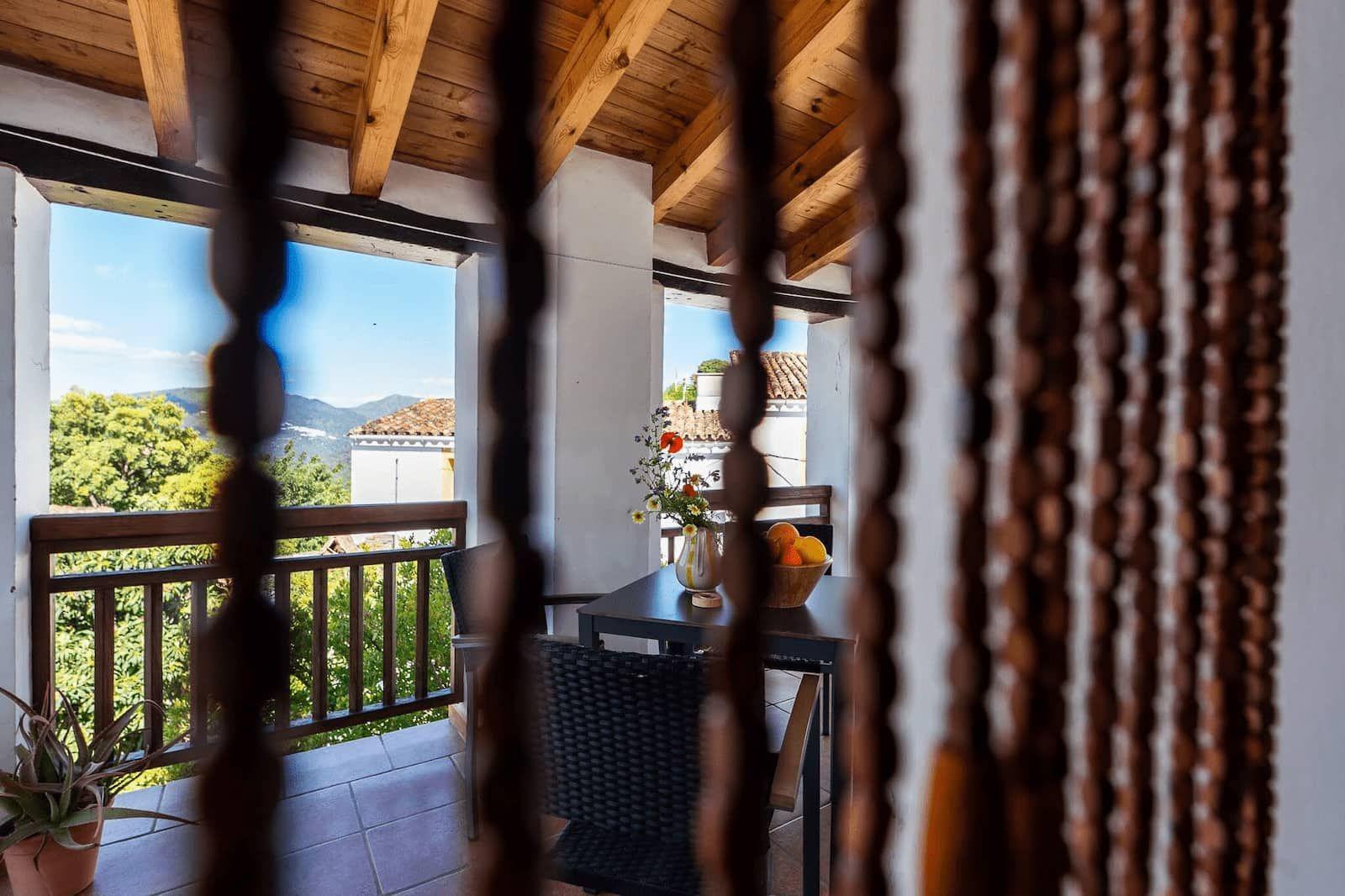 Terrace with wooden ceiling and mountain views, seen through a bead curtain