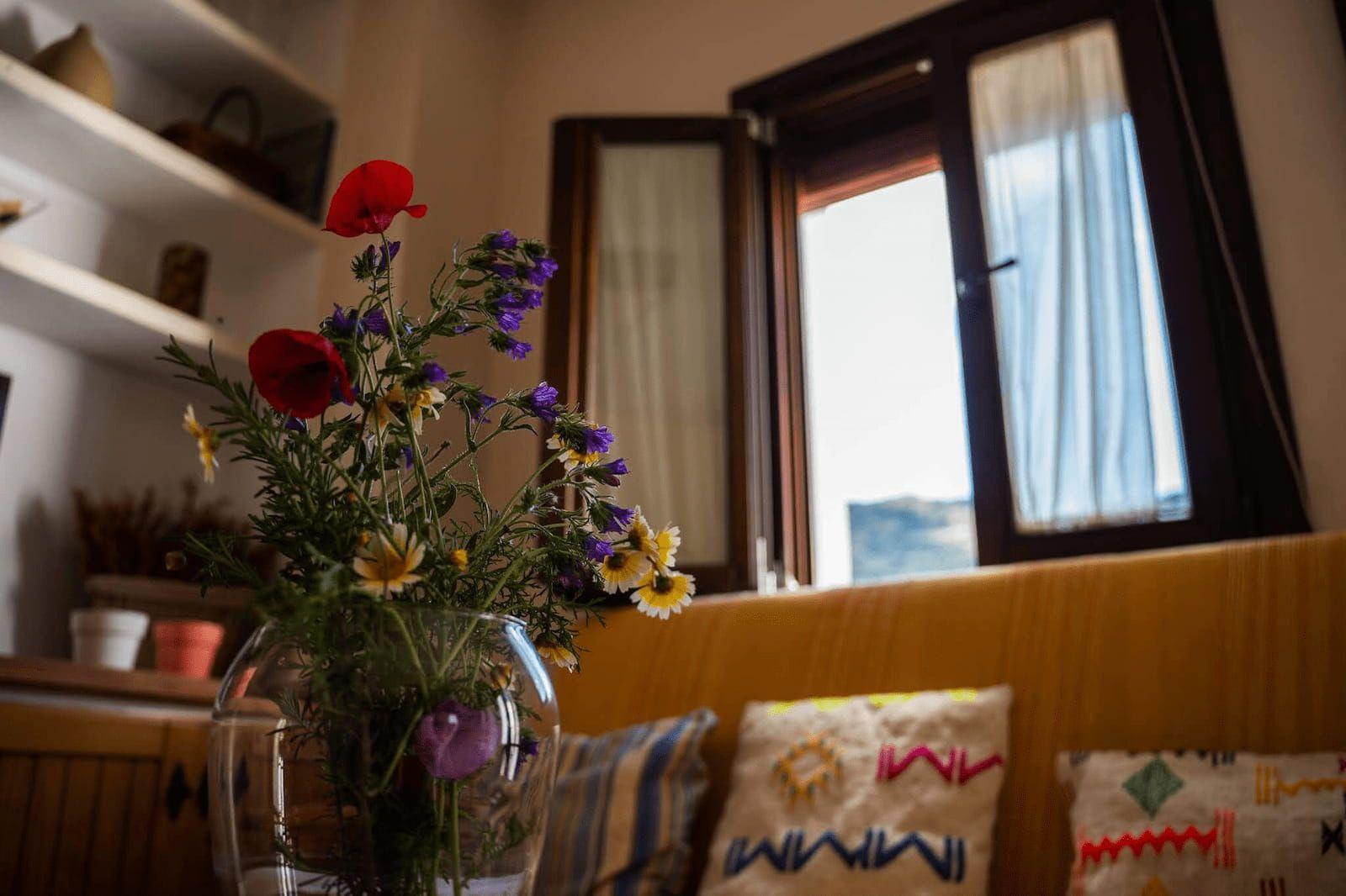 Cozy living room with sunlight, fresh flowers, and decorated sofa at Rooral coliving, ideal for remote workers and digital nomads