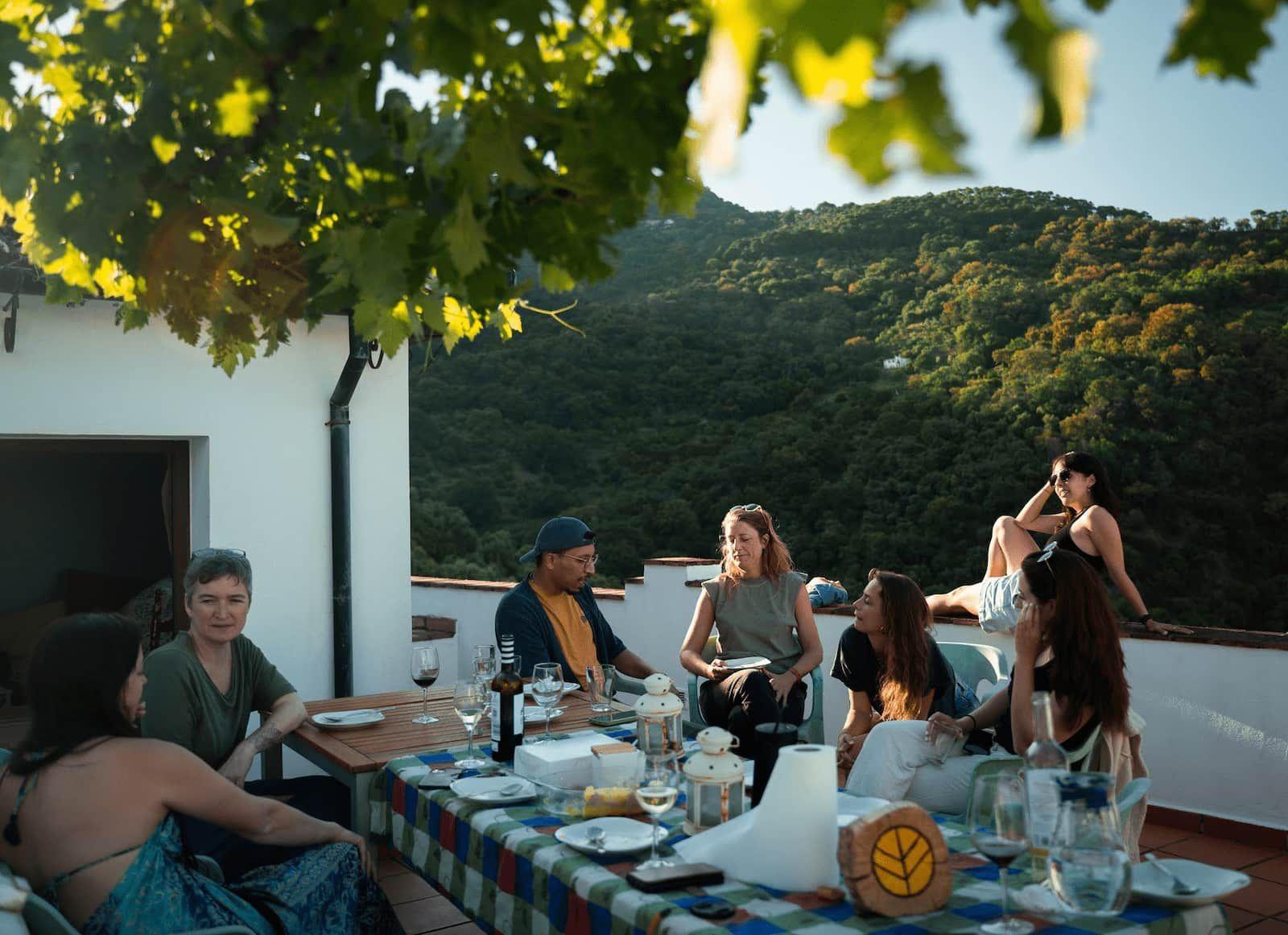 Rooral coliving community having lunch together on a rooftop near Malaga, Spain, enjoying social time and village views