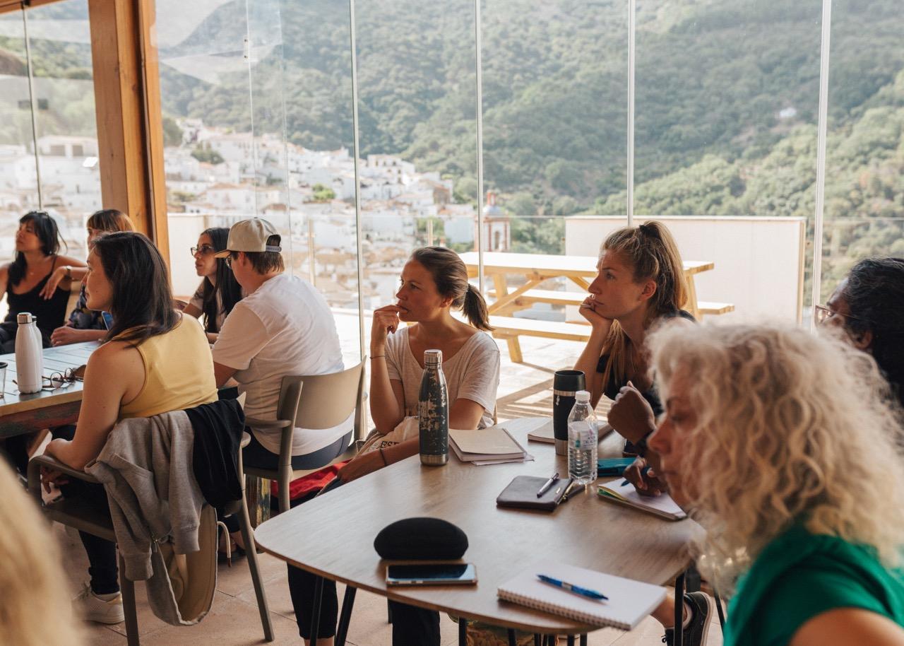 Remote workers and digital nomads participate in a skill-sharing session at the rural coworking space in Benarraba Andalusia, set against the backdrop of the white village, scenic nature and deep forests.