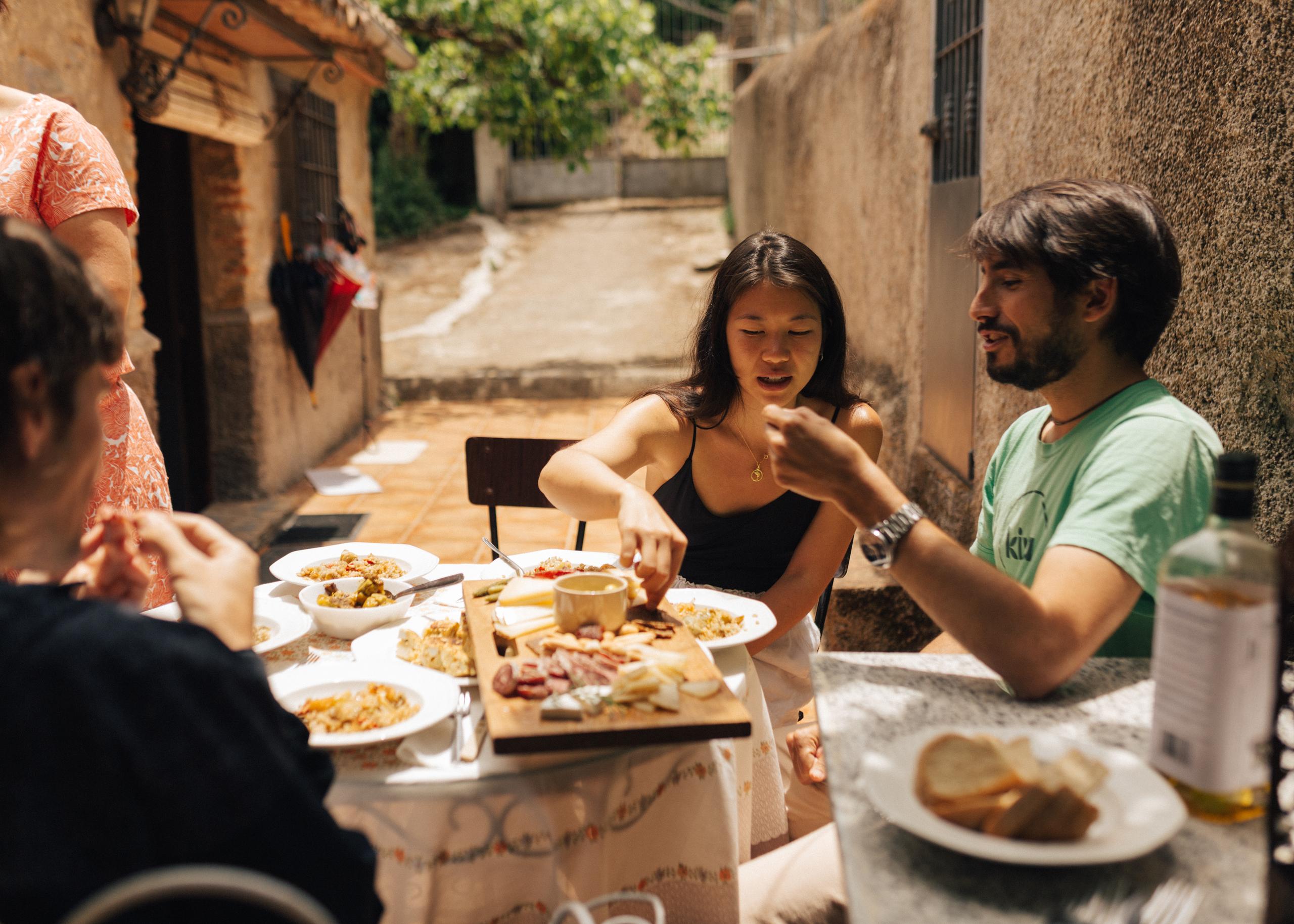 Savoring a community dinner on the terrace of our coliving space in Benarraba, rural Malaga, complemented by olive oil, local cheeses, and quinoa salad