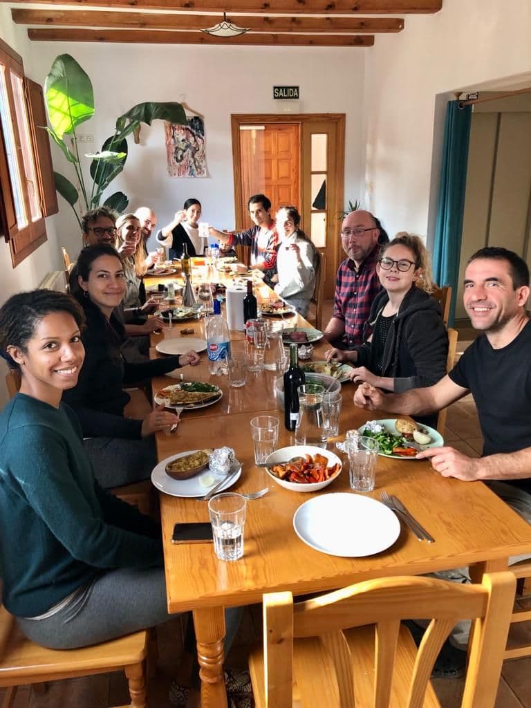 Community members sharing a meal together around the long dining table
