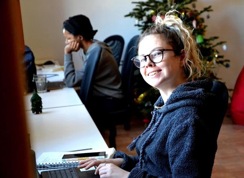 Guest smiling while working on a laptop in the shared office space decorated for Christmas