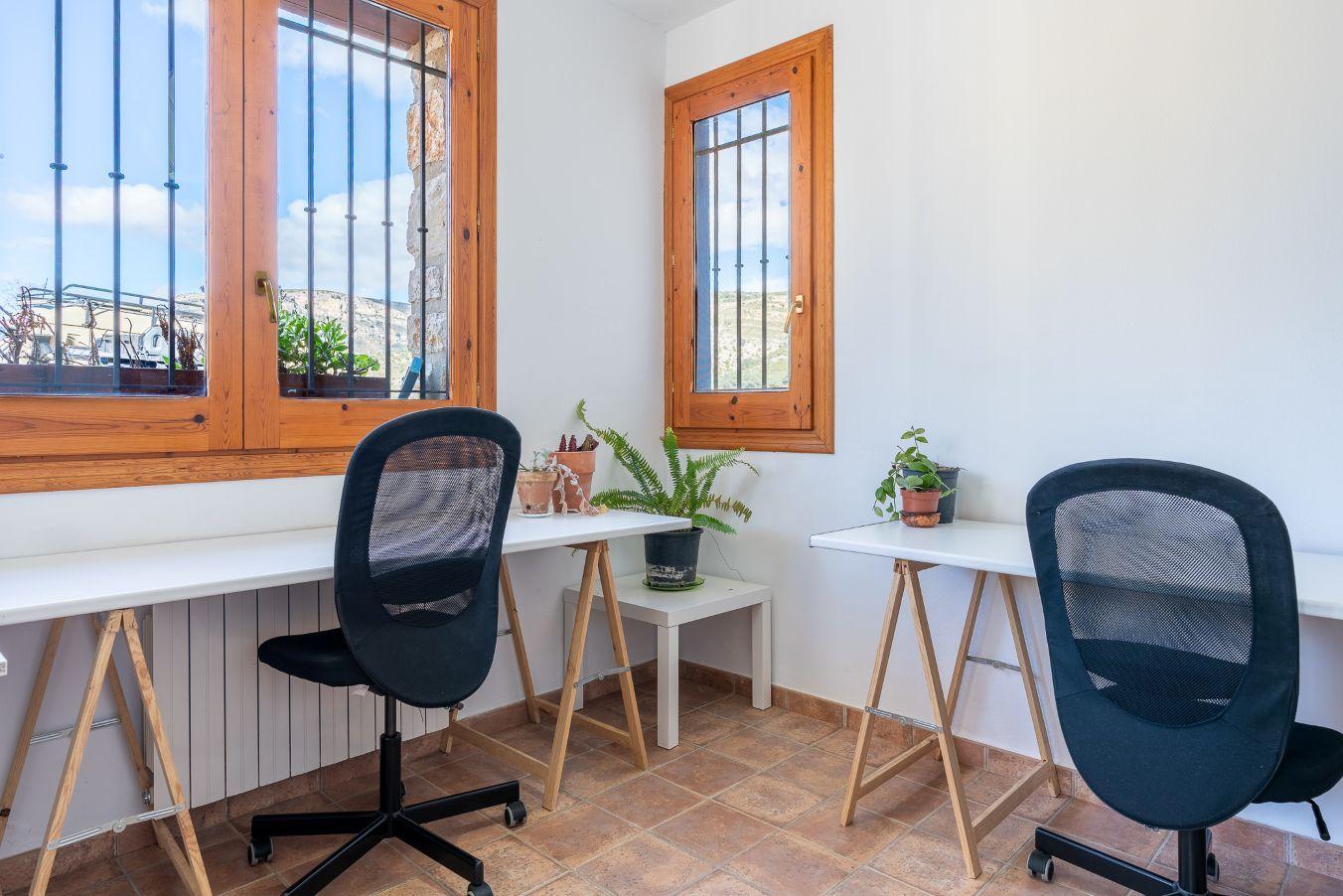 Small office/meeting room with two desks, chairs, and windows with natural light